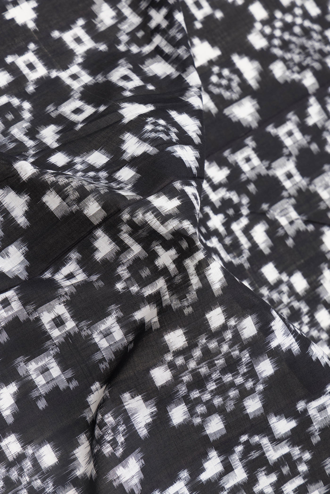 Close up of Black Dual Tone Double Ikat Saree with Ikat Print on the body and Thread Border.  displaying folds