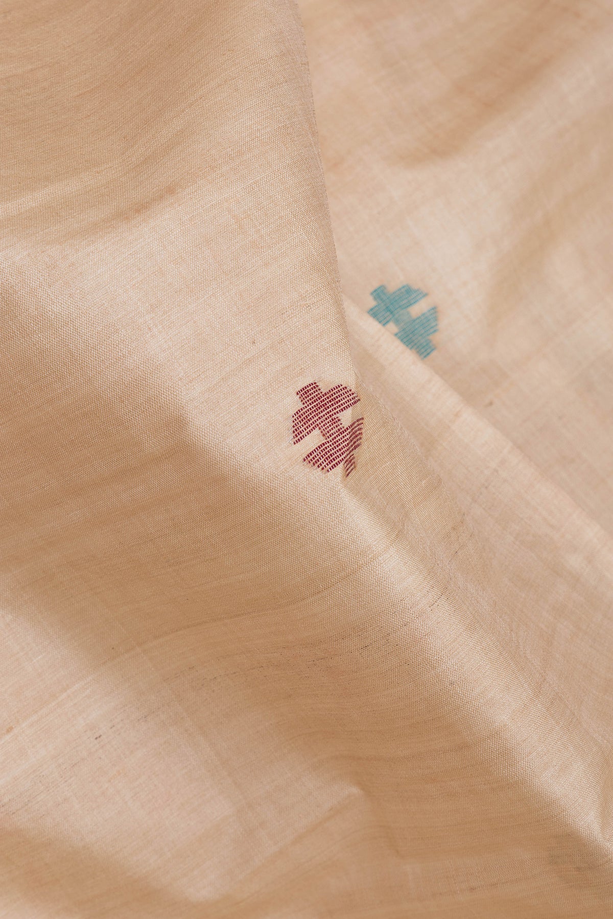 Close up of Beige Tussar Silk Saree with Thread Butta on the body and Plain Border.  displaying folds