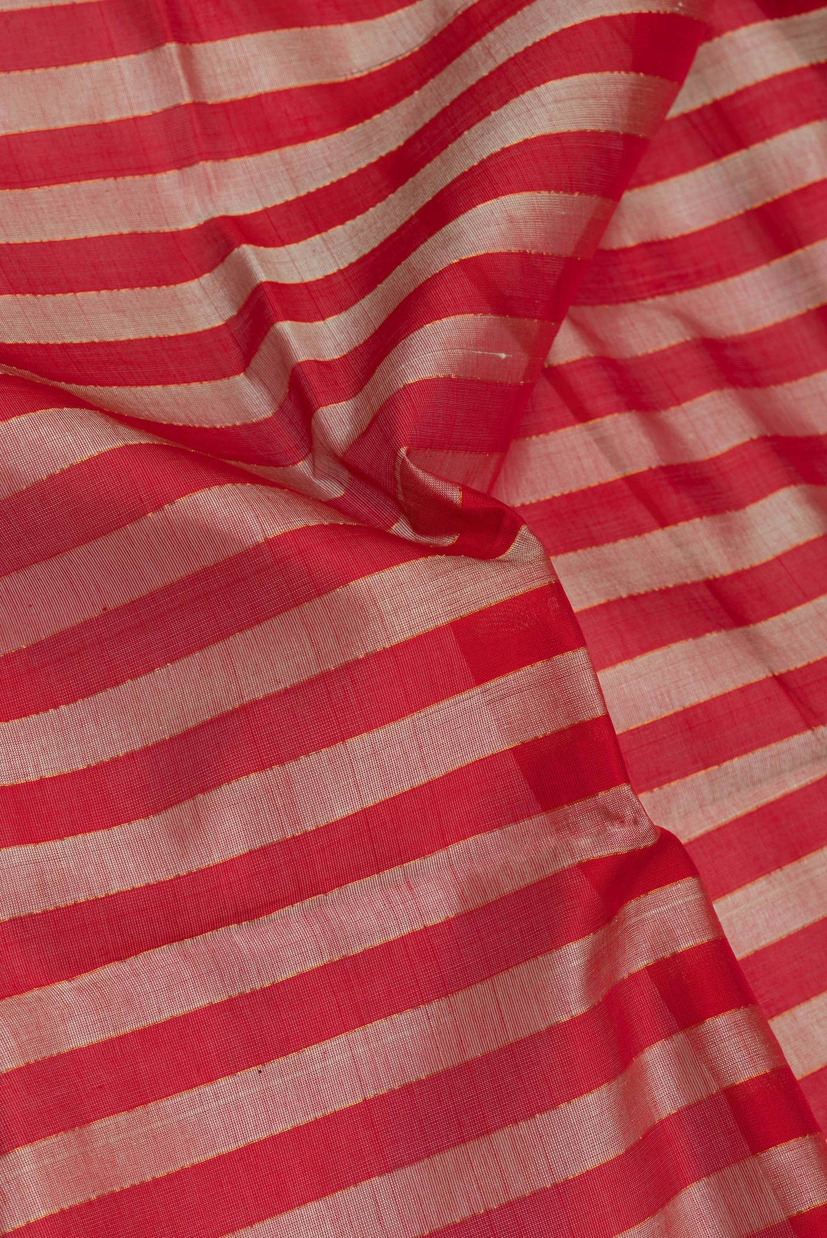 Close up of Red Silk Cotton Saree with Stripes on the body and Zari Border.  displaying folds