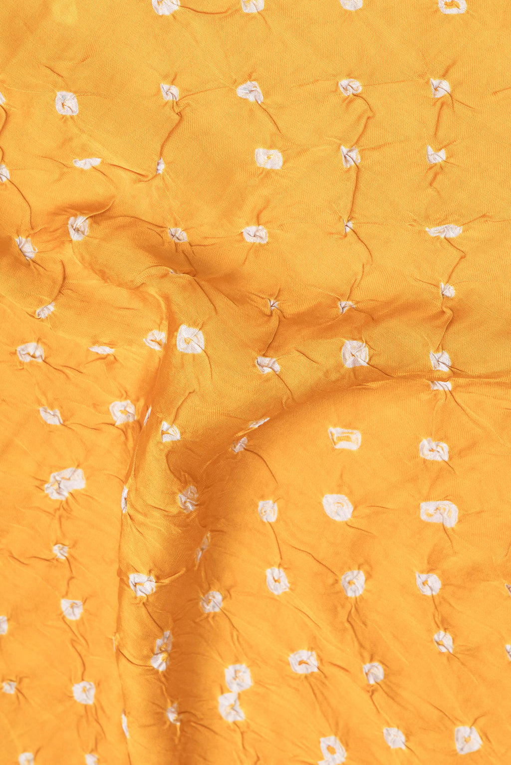 Close up of Yellow Blended Satin Crepe Saree with Bandhani Print on the body and Without Border.  displaying folds