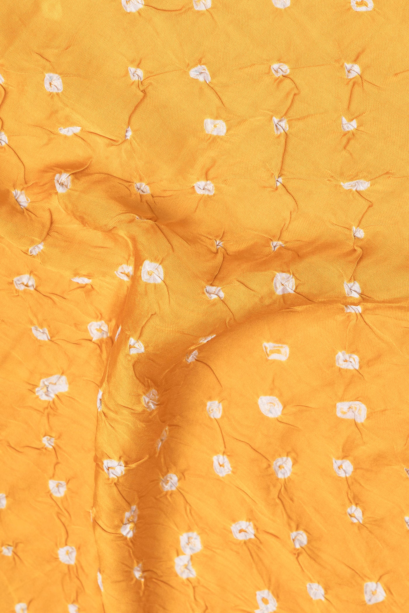 Close up of Yellow Blended Satin Crepe Saree with Bandhani Print on the body and Without Border.  displaying folds