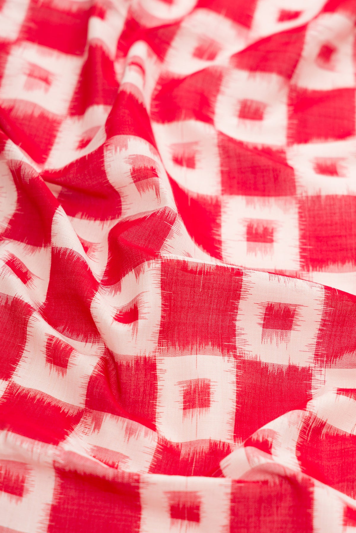 Close up of Red Dual Tone Double Ikat Saree with Ikat Print on the body and Plain Border.  displaying folds