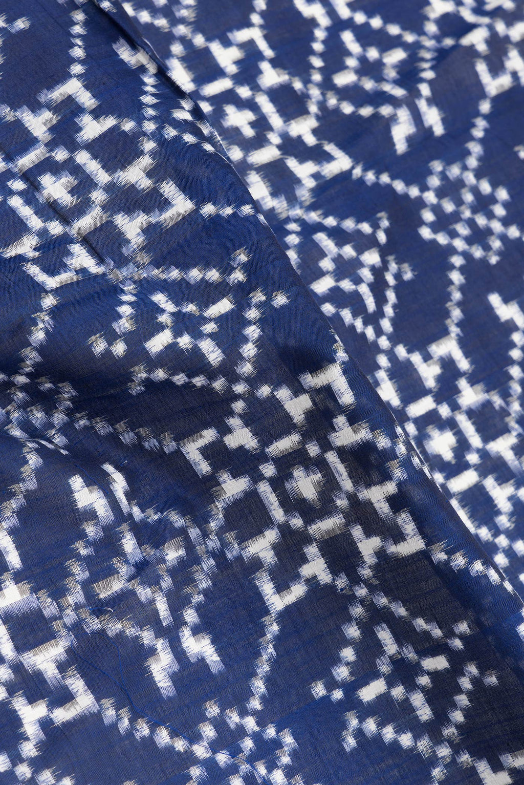 Close up of Navy Blue Dual Tone Double Ikat Saree with Ikat Print on the body and Thread Border.  displaying folds