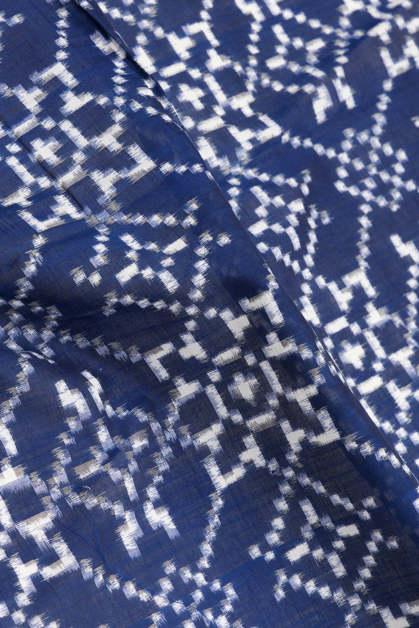 Close up of Navy Blue Dual Tone Double Ikat Saree with Ikat Print on the body and Thread Border.  displaying folds