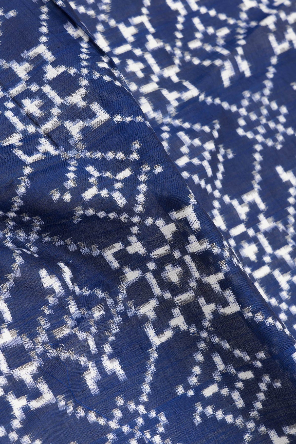 Close up of Navy Blue Dual Tone Double Ikat Saree with Ikat Print on the body and Thread Border.  displaying folds