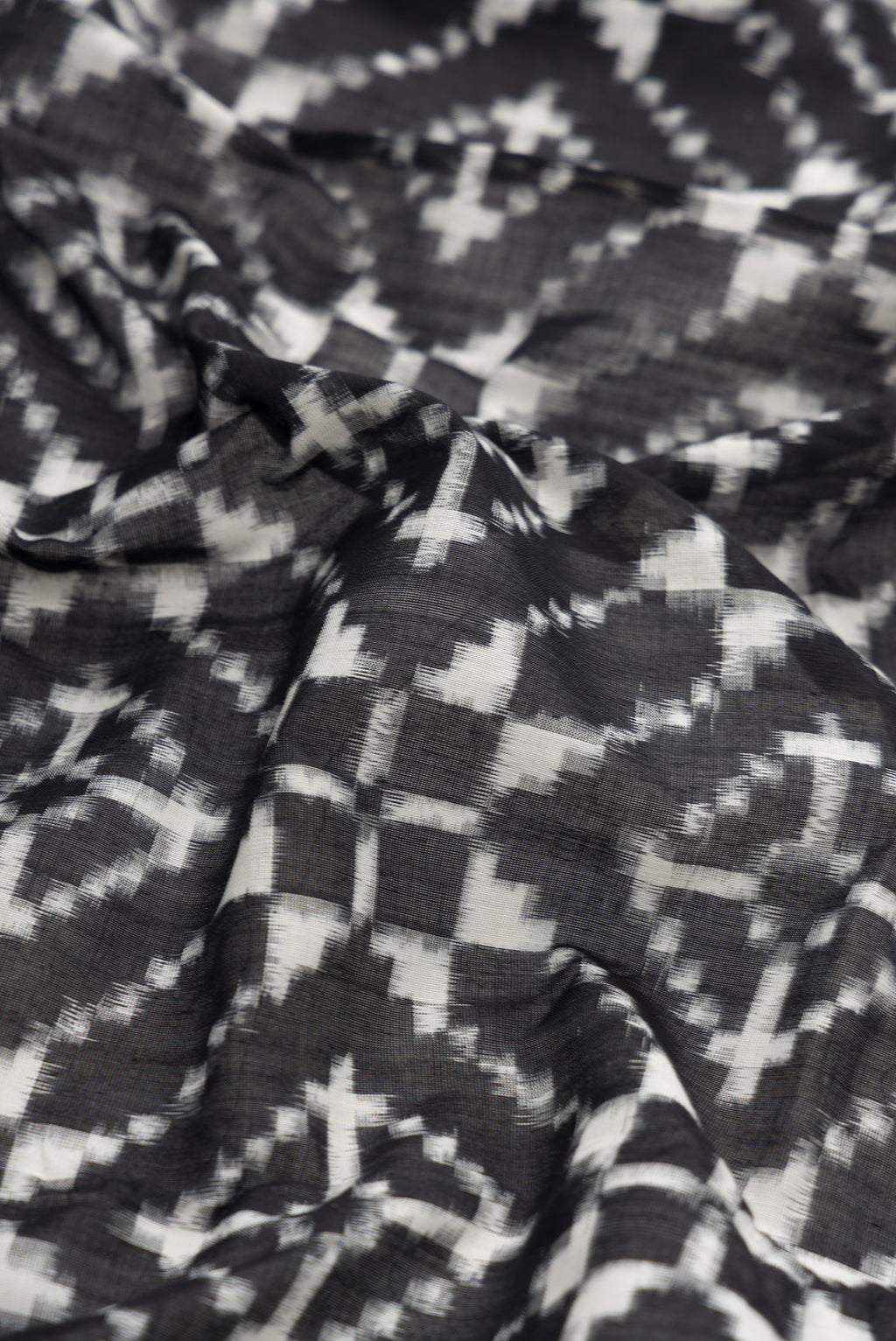 Close up of Black Dual Tone Double Ikat Saree with Ikat Print on the body and Plain Border.  displaying folds