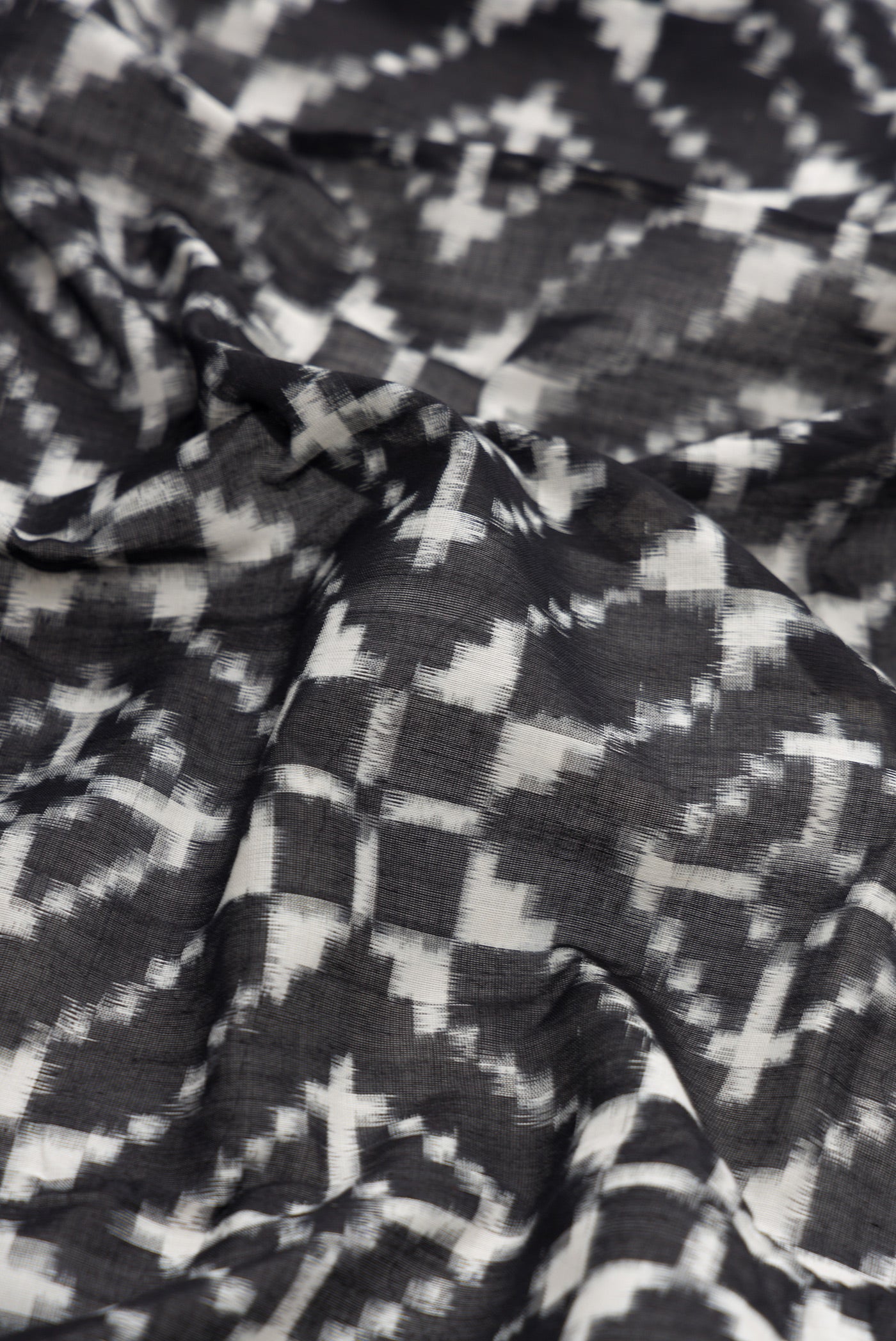 Close up of Black Dual Tone Double Ikat Saree with Ikat Print on the body and Plain Border.  displaying folds