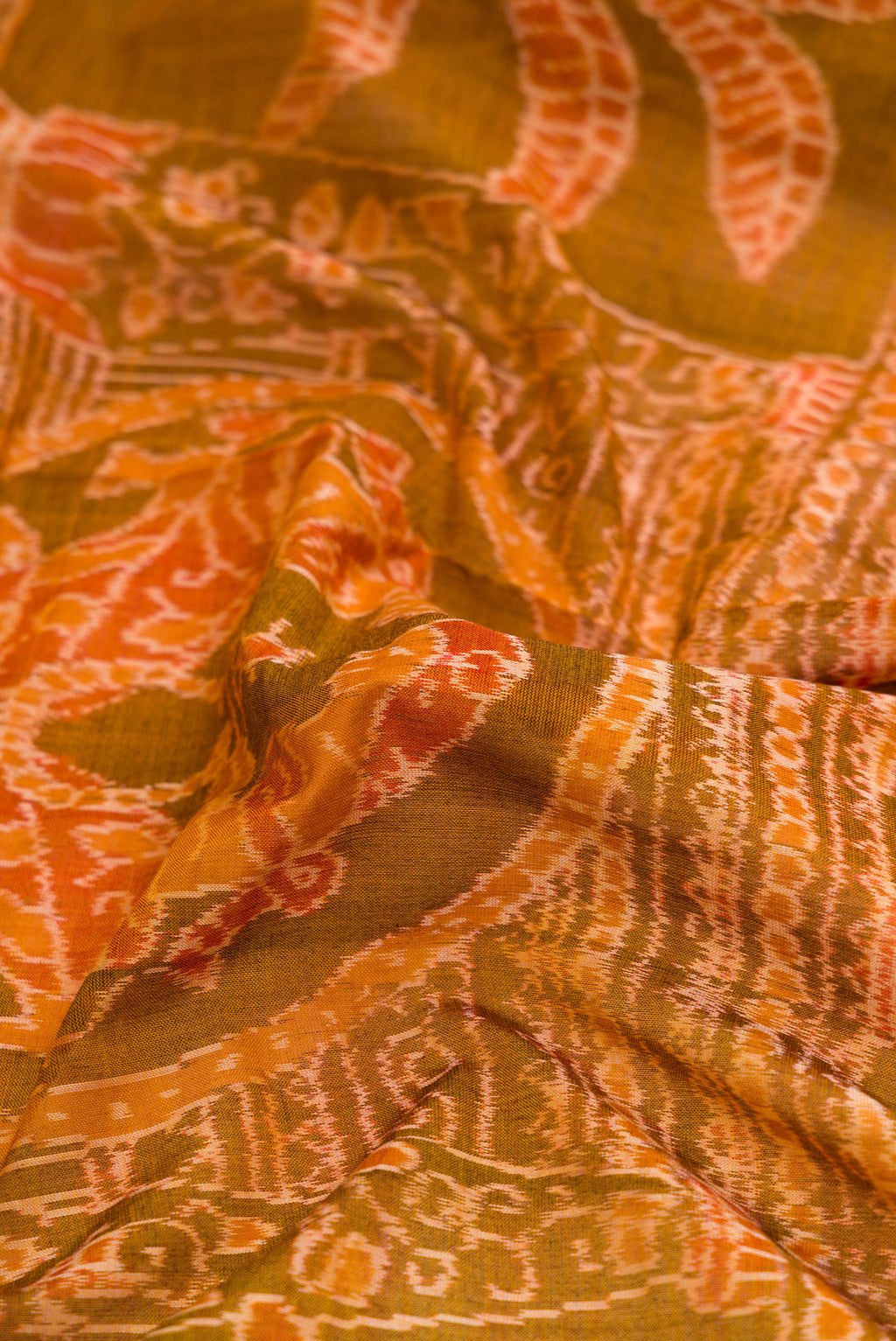Close up of Mustard Dual Tone Double Ikat Saree with Ikat Print on the body and Thread Border.  displaying folds