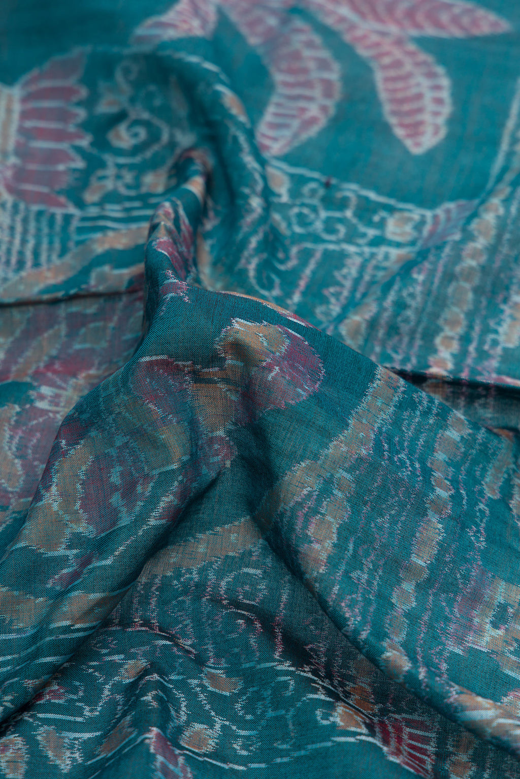 Close up of Peacock Blue Dual Tone Double Ikat Saree with Ikat Print on the body and Thread Border.  displaying folds