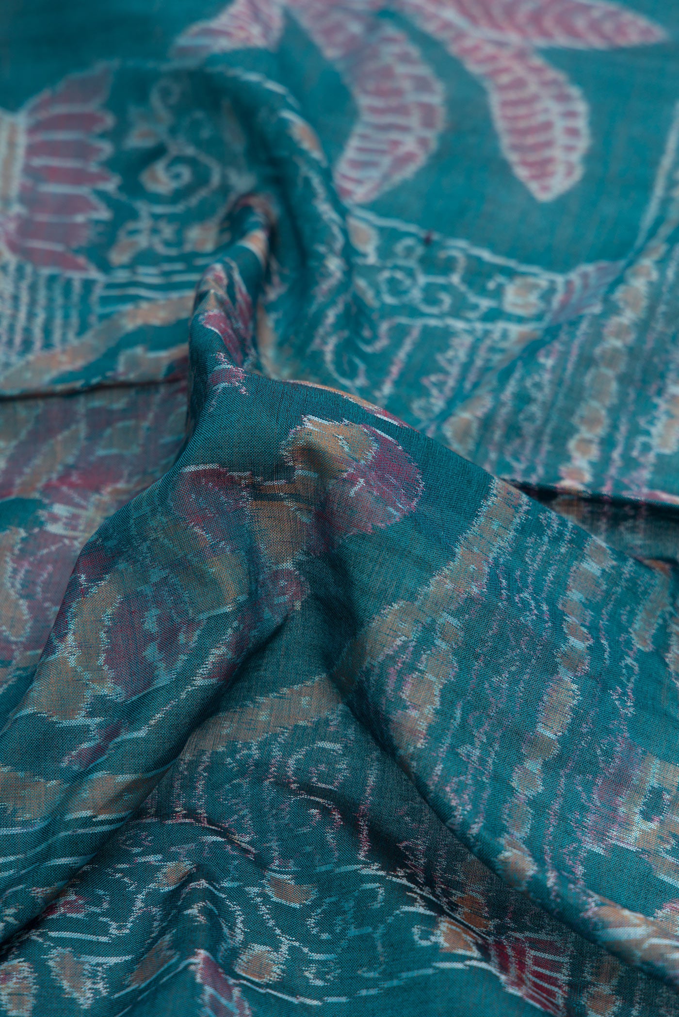 Close up of Peacock Blue Dual Tone Double Ikat Saree with Ikat Print on the body and Thread Border.  displaying folds