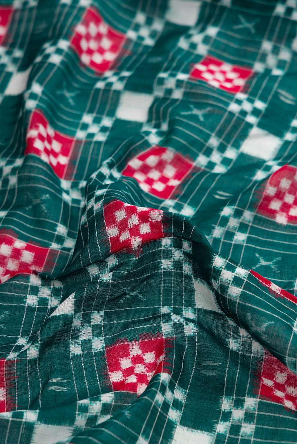 Close up of Bottle Green Dual Tone Double Ikat Saree with Ikat Print on the body and Thread Border.  displaying folds
