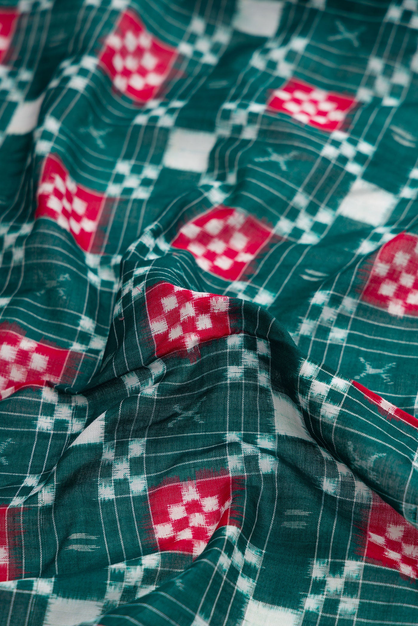 Close up of Bottle Green Dual Tone Double Ikat Saree with Ikat Print on the body and Thread Border.  displaying folds