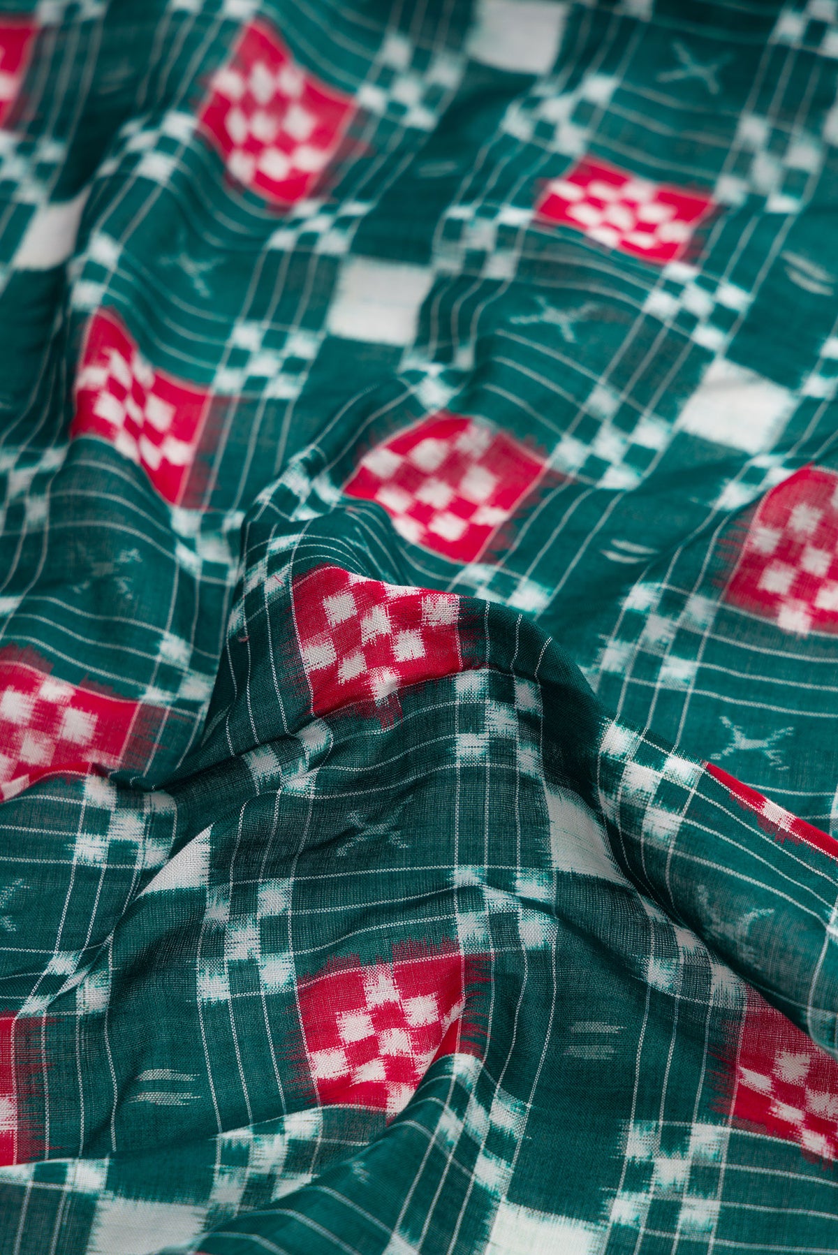 Close up of Bottle Green Dual Tone Double Ikat Saree with Ikat Print on the body and Thread Border.  displaying folds