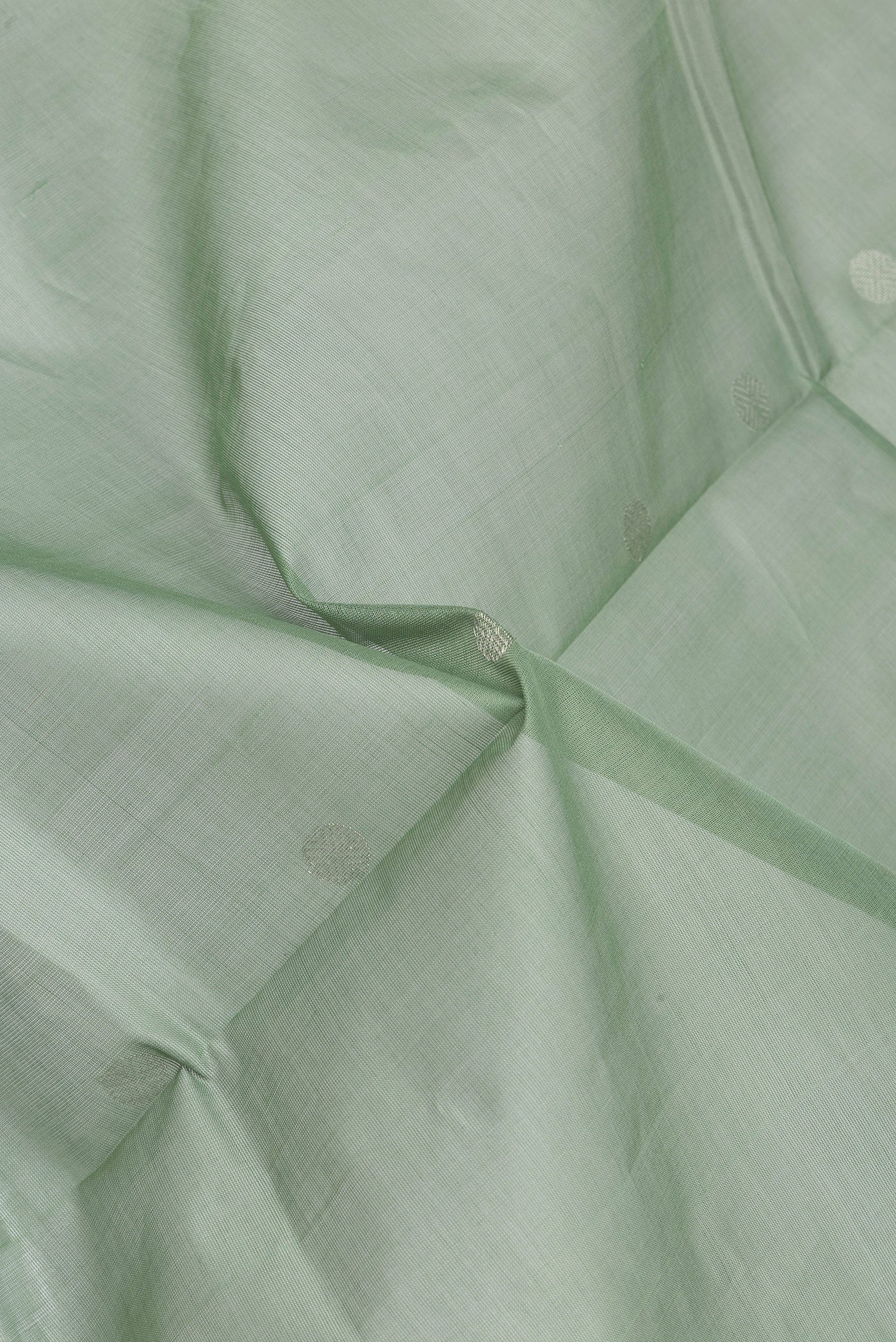 Close up of Pista Green Uppada Cotton Saree with Zari Butta on the body and Zari Border.  displaying folds