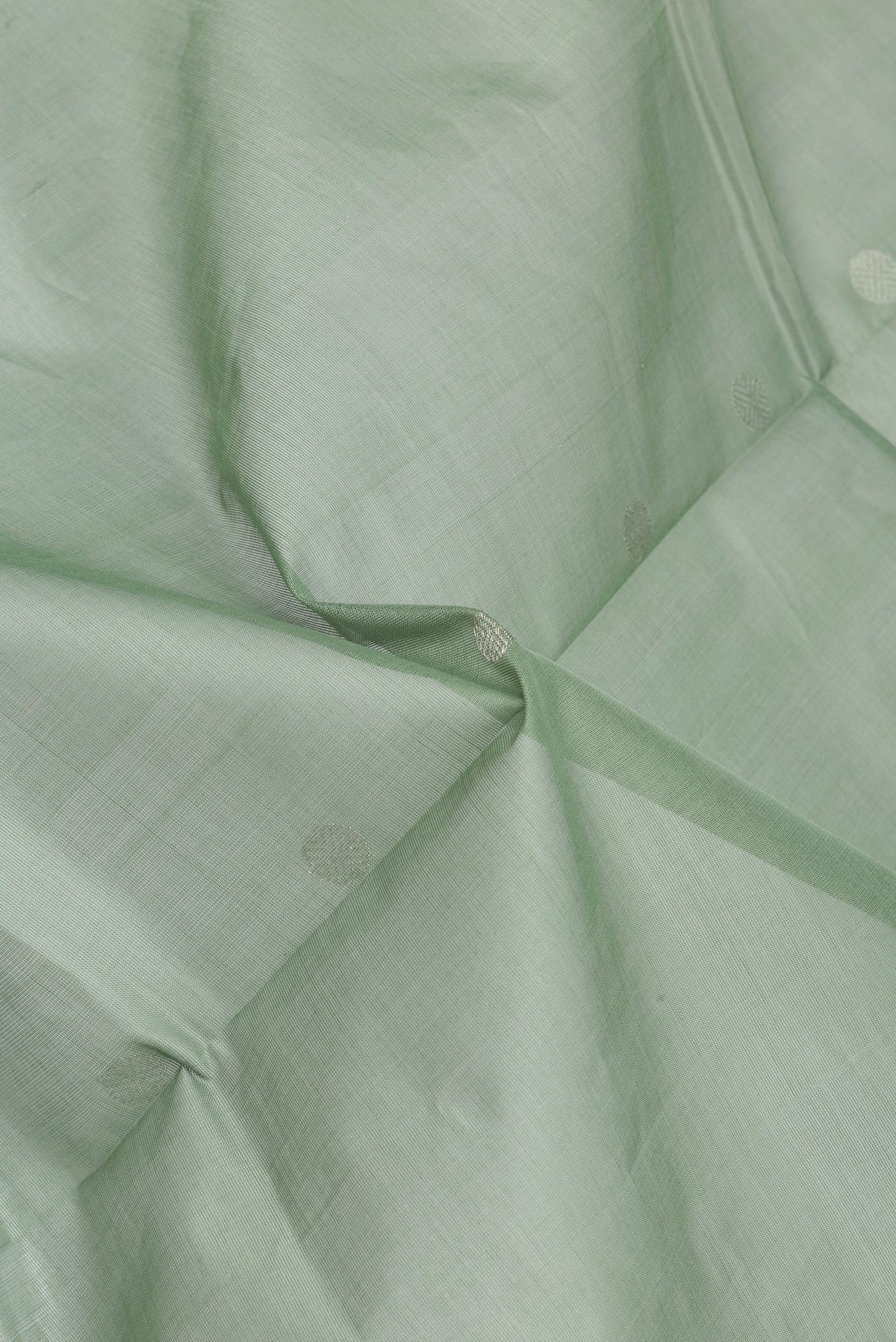 Close up of Pista Green Uppada Cotton Saree with Zari Butta on the body and Zari Border.  displaying folds
