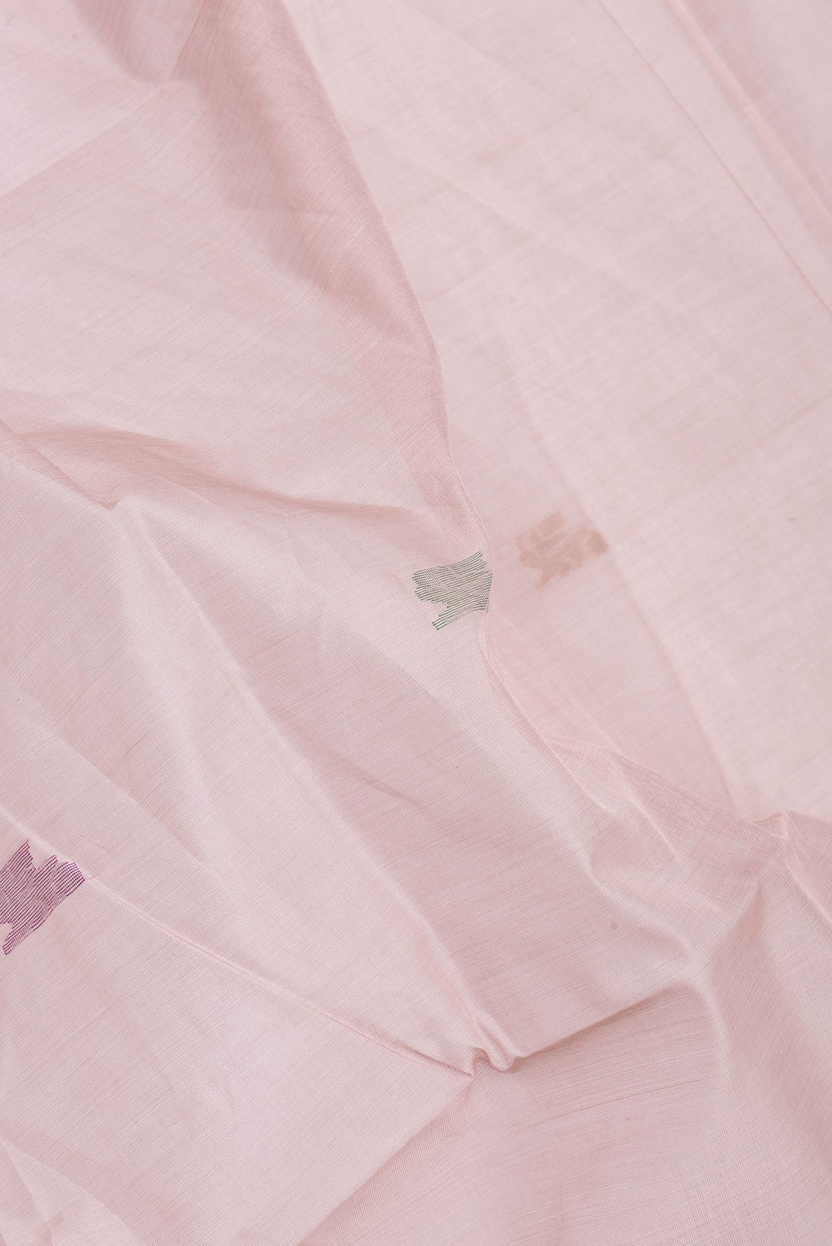 Close up of Rose Gold Uppada Cotton Saree with Zari And Thread Butta on the body and Zari Border.  displaying folds