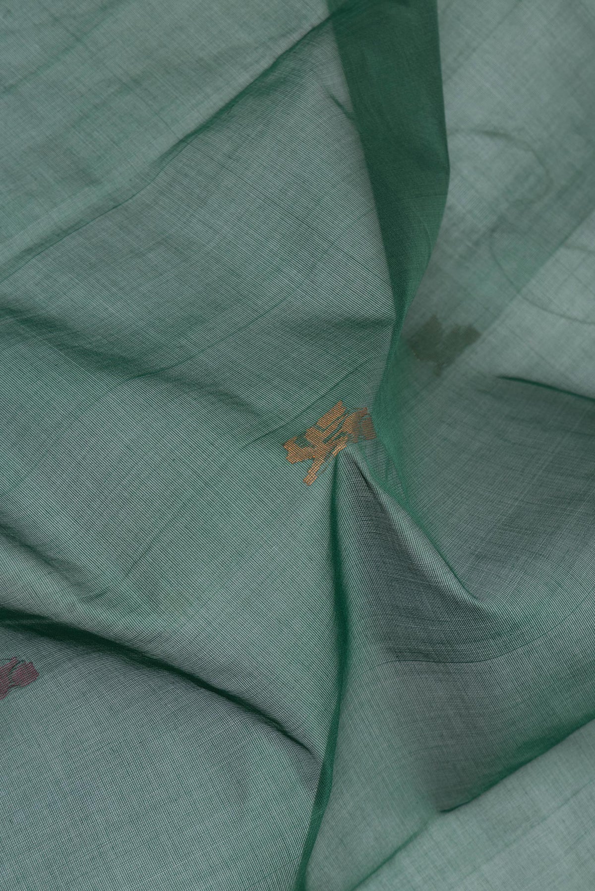 Close up of Bottle Green Uppada Cotton Saree with Zari And Thread Butta on the body and Zari Border.  displaying folds