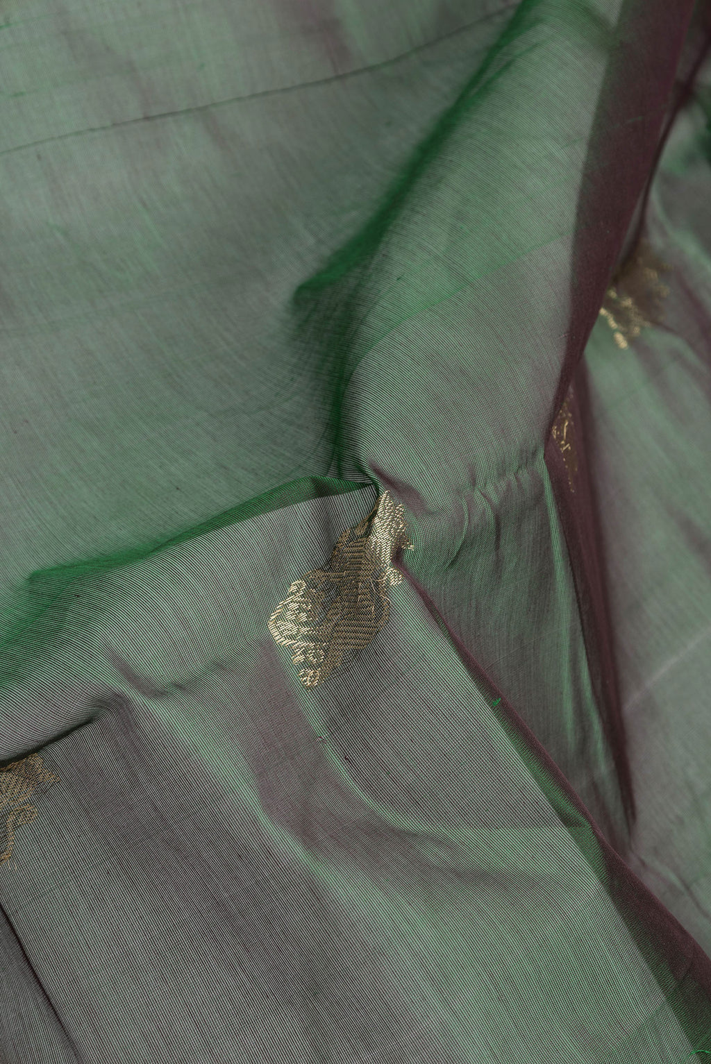 Close up of Bottle Green Dual Tone Silk Cotton Saree with Zari Butta on the body and Zari And Thread Border.  displaying folds