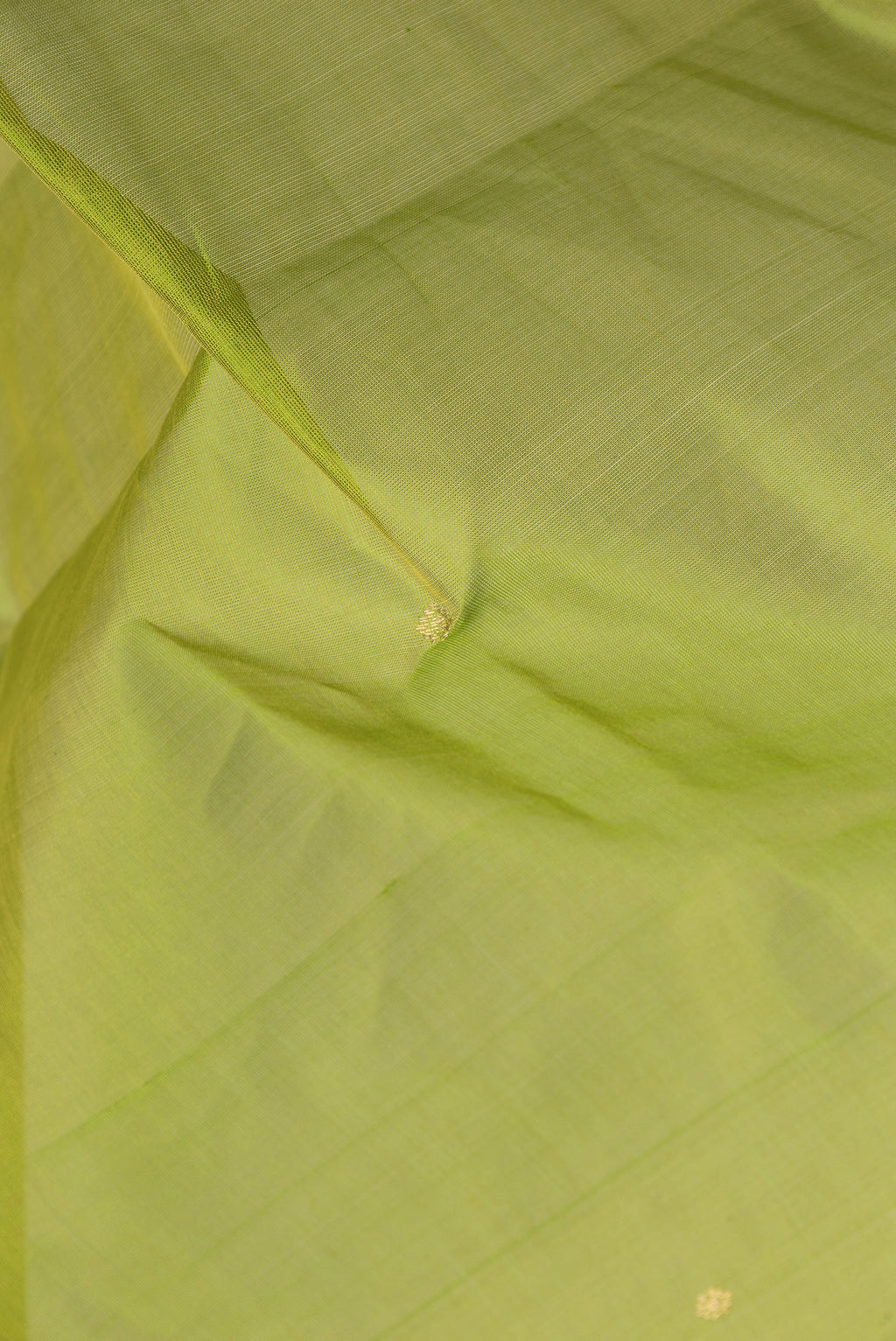 Close up of Parrot Green Dual Tone Silk Cotton Saree with Zari Butta on the body and Zari Border.  displaying folds