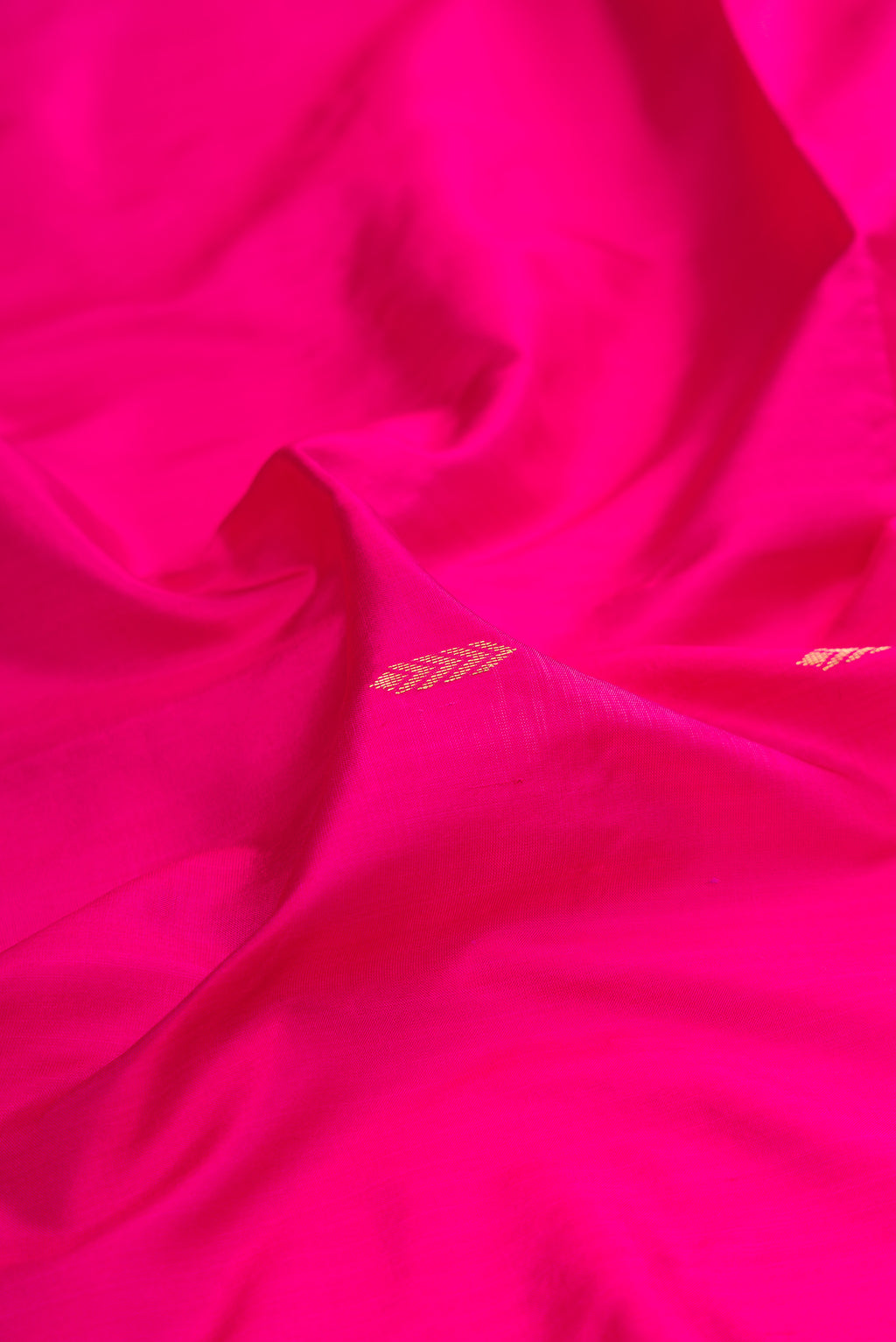 Close up of Rani Pink Maheshwari Silk Saree with Zari Butta on the body and Zari Border.  displaying folds