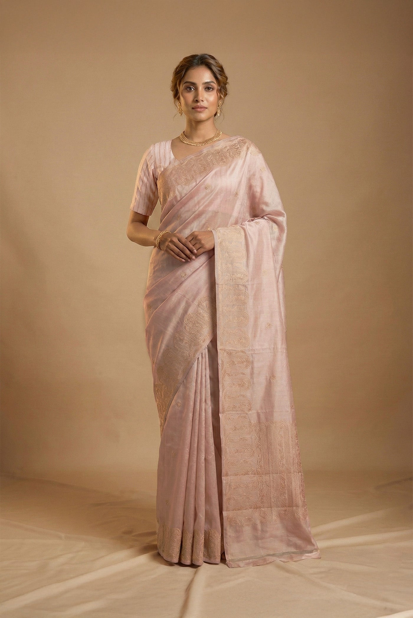 Model wearing a Mandhara, handwoven in Katan silk, brings together kadhua weaving and delicate meenakari detailing Crafted in gold zari with silver accents, the saree draws from Art Nouveau florals and the concentric forms of Dhokra metal craft Wavy, concentric borders with floral vines frame the design, while tiny silver-meenakari butis dot the body The pallu completes the saree with elongated floral panels, lending a balanced, composed finish