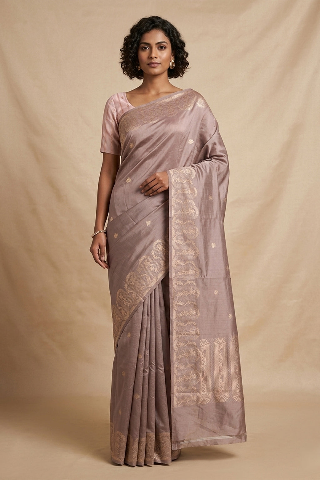 Model wearing a Mandhara, handwoven in Katan silk, brings together kadhua weaving and delicate meenakari detailing. Crafted in gold zari with silver accents, the saree draws from Art Nouveau florals and the concentric forms of Dhokra metal craft. Wavy, concentric borders with floral vines frame the design, while tiny silver-meenakari butis dot the body. The pallu completes the saree with elongated floral panels, lending a balanced, composed finish.
