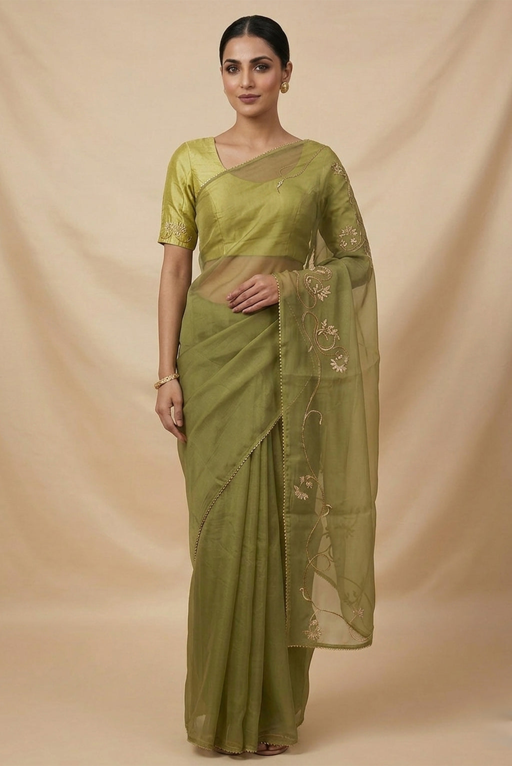Model wearing a In Mira, pure silk organza becomes a canvas for antique gold and pani zari, brought to life through fine dabka and aari embroidery. The pallu takes inspiration from the bull masks of the Cameroon Grasslands, translating their powerful curves into graceful motifs layered with florals and Art Nouveau lines. Dual-tone zari and detailed shoulders lend the saree depth, movement, and a refined festive glow.