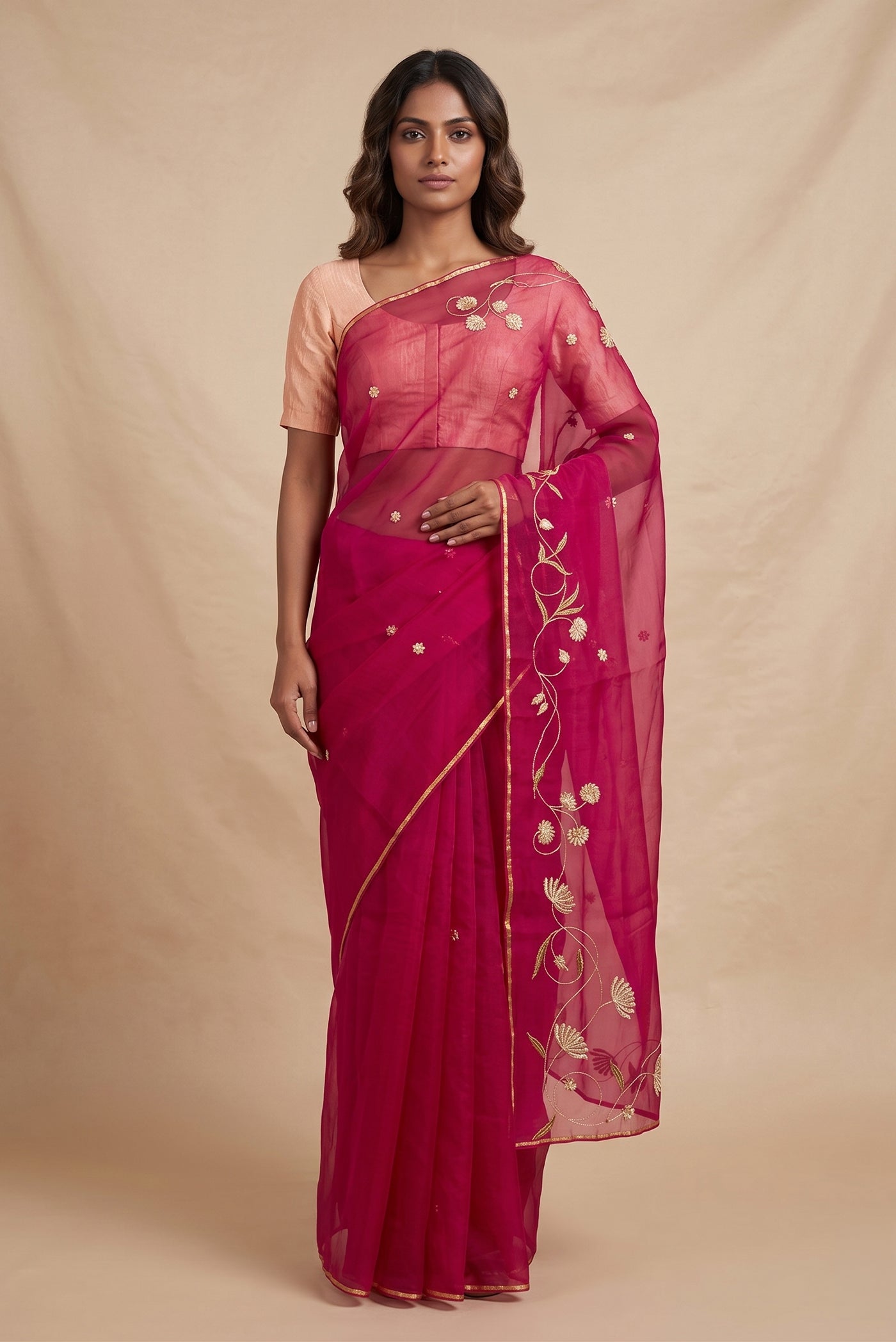Model wearing a Bahar, crafted in silk organza, features delicate pani-zari enriched with zardozi, gota work, and dabka embroidery. Its defining element is an off-center floral vine running vertically through the body, breaking symmetry with quiet intent. Inspired by Art Nouveau?s flowing lines, the vine is rendered in slender leaves, zari chain-stitched stems, and alternating gota and zardozi flowers. The pallu trails gently onto the body in scattered embroidered blooms.
