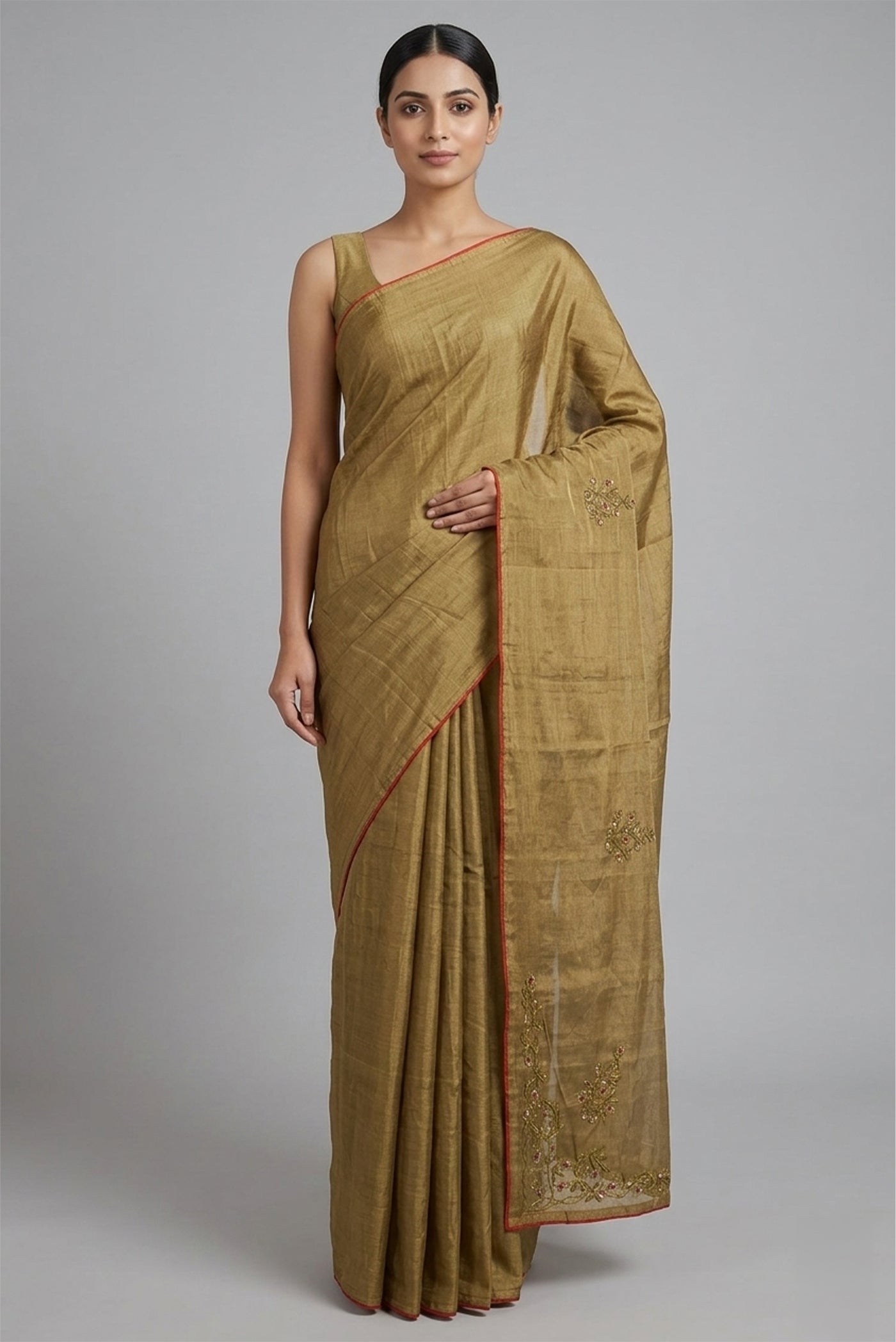 Model wearing a Rumana is crafted in delicate tissue enriched with antique-gold zardozi, brought to life through dabka, sequins, and coloured beads. The pallu unfolds with konia motifs and flowing pomegranate vines, anchored by a drop-shaped buta rendered in a stylised pomegranate form. The body carries evenly placed butas that continue into the pleats, lending the saree a gentle, composed rhythm. A classic gota trim completes this elegant expression of symbolic craft.