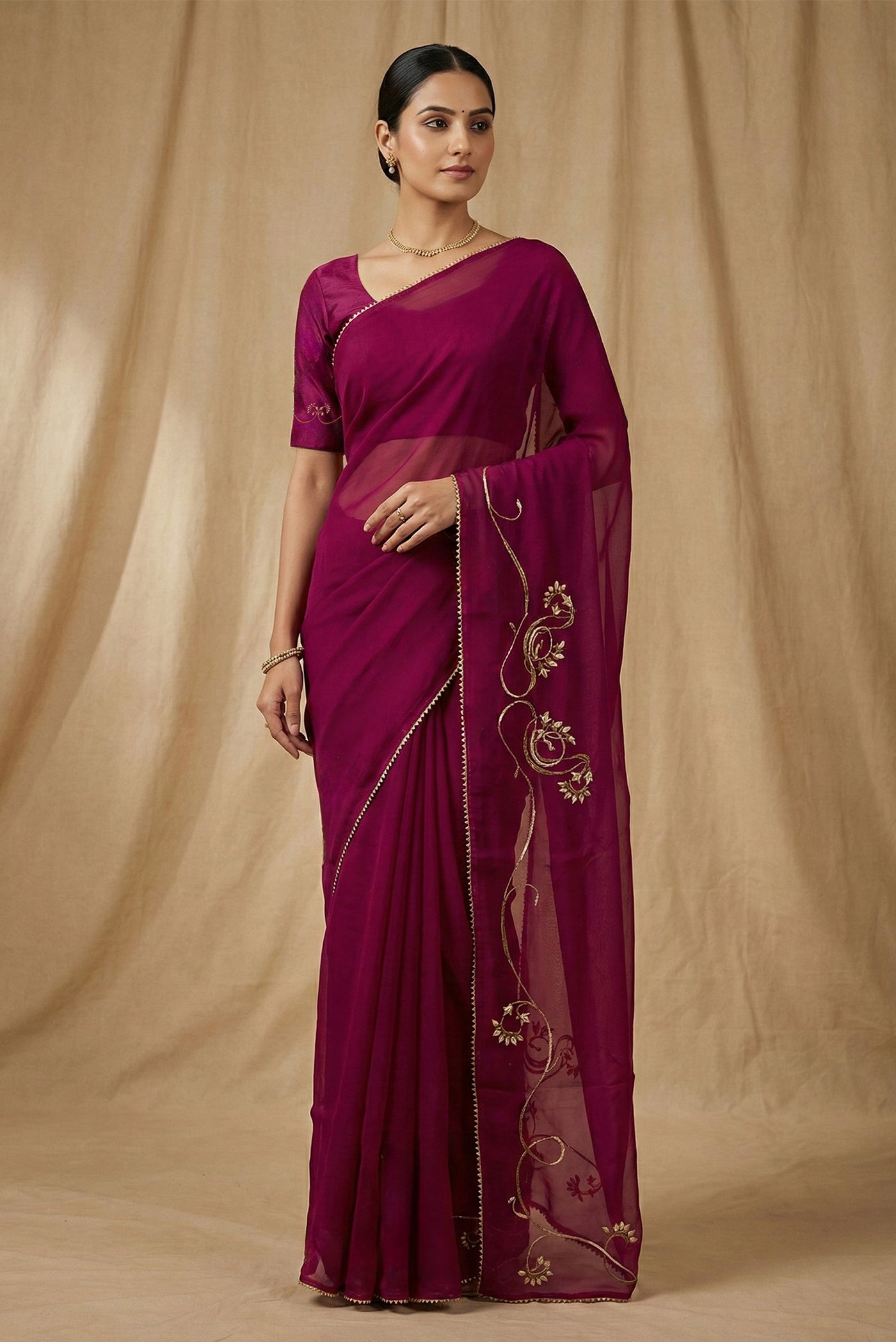 Model wearing a In Mira, pure silk organza becomes a canvas for antique gold and pani zari, brought to life through fine dabka and aari embroidery The pallu takes inspiration from the bull masks of the Cameroon Grasslands, translating their powerful curves into graceful motifs layered with florals and Art Nouveau lines Dual-tone zari and detailed shoulders lend the saree depth, movement, and a refined festive glow