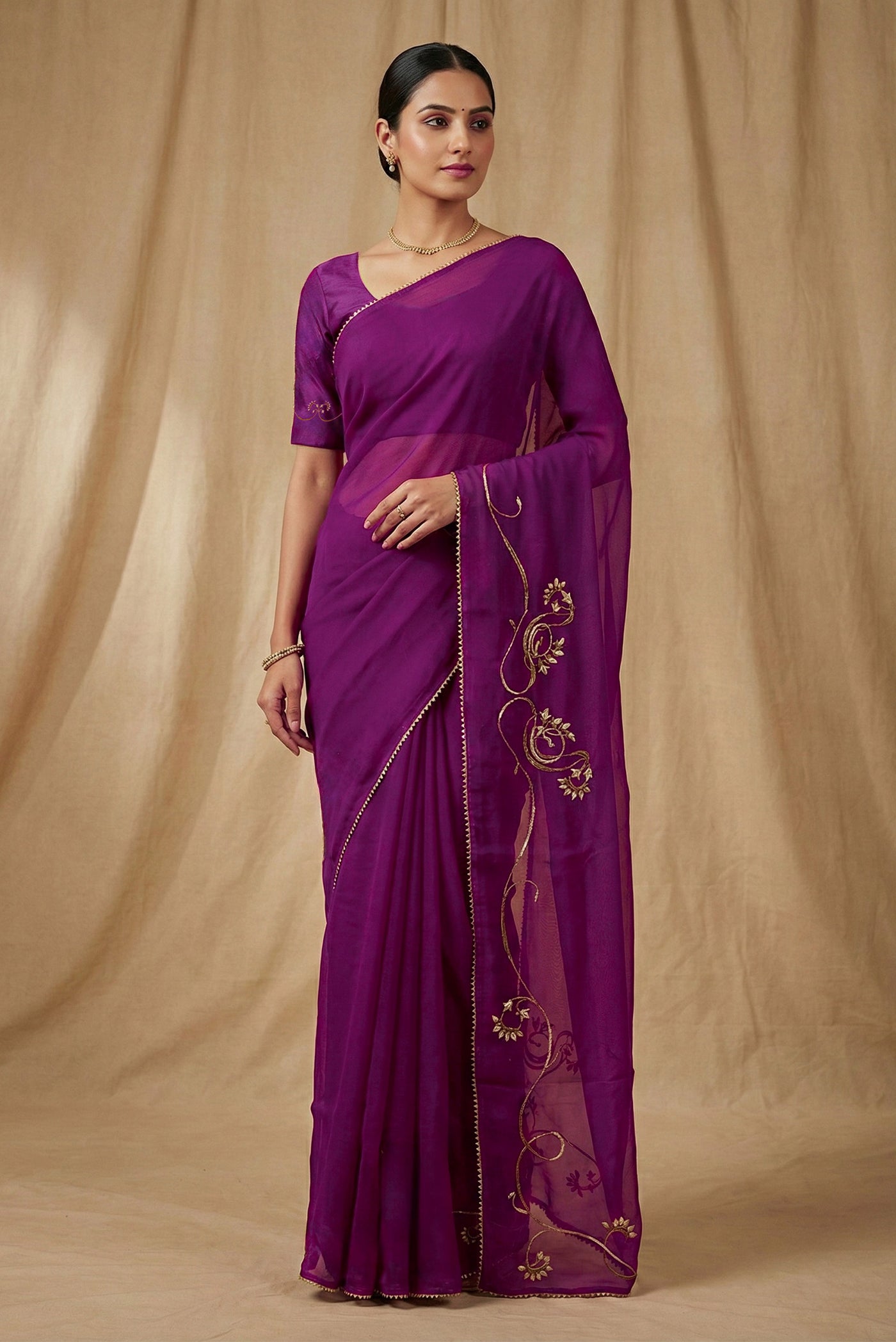 Model wearing a In Mira, pure silk organza becomes a canvas for antique gold and pani zari, brought to life through fine dabka and aari embroidery The pallu takes inspiration from the bull masks of the Cameroon Grasslands, translating their powerful curves into graceful motifs layered with florals and Art Nouveau lines Dual-tone zari and detailed shoulders lend the saree depth, movement, and a refined festive glow