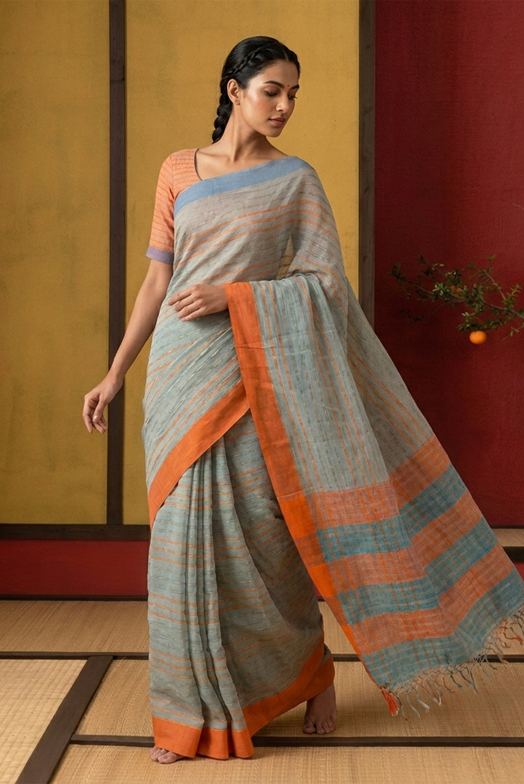 Model wearing a Mishri, a celebration of summer in Bengal cotton, is woven in fine 60-count cotton and drapes with natural comfort. Soft stripes move in gentle linear patterns across the fabric, creating a lively yet balanced design. The fine checks they form are a gentle reminder of crystal sugar, lending the saree its name. Light, breathable, and effortlessly wearable for sunlit days.