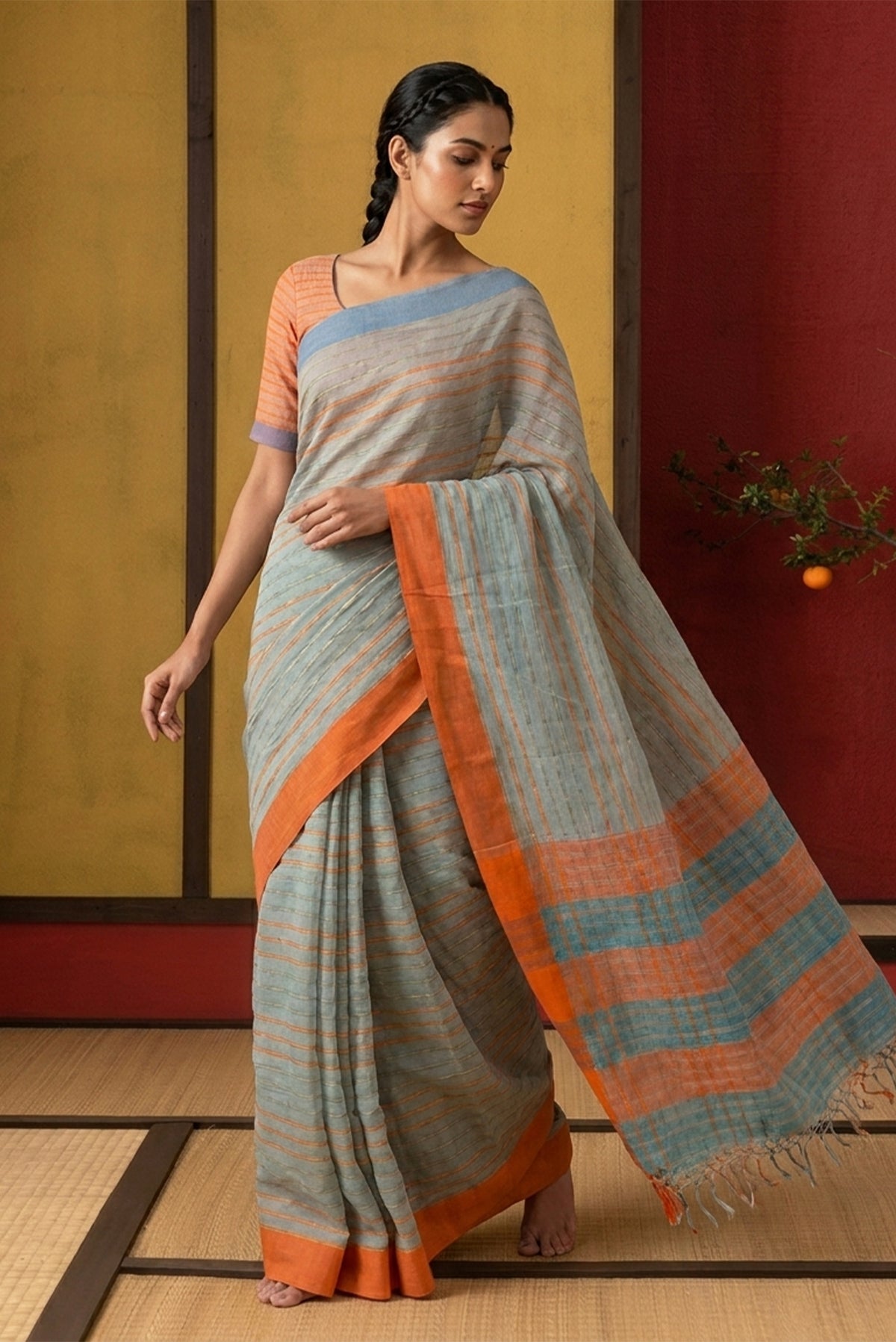 Model wearing a Mishri, a celebration of summer in Bengal cotton, is woven in fine 60-count cotton and drapes with natural comfort. Soft stripes move in gentle linear patterns across the fabric, creating a lively yet balanced design. The fine checks they form are a gentle reminder of crystal sugar, lending the saree its name. Light, breathable, and effortlessly wearable for sunlit days.