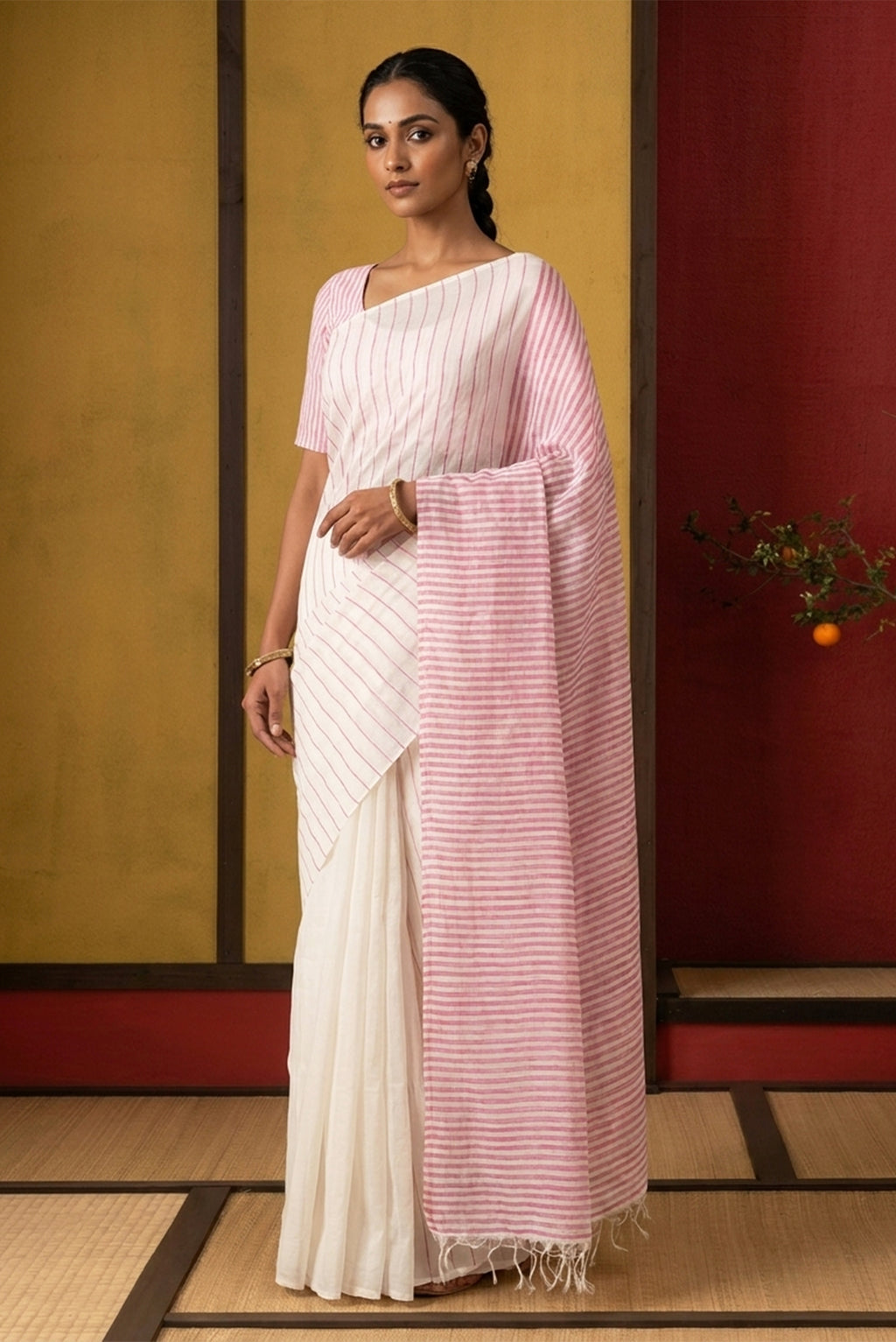Model wearing a Mogra is designed to feel light and effortless. Its muted pastels draw from the soft, fragrant bloom of jasmine, mogra, giving the saree its name. Intentional colour-blocking lends it a distinct presence, while contrasting panels shape the pleats and pallu with quiet structure. Fine vertical stripes add subtle detail, and silver zari stripes on the pallu offer a gentle, radiant highlight.