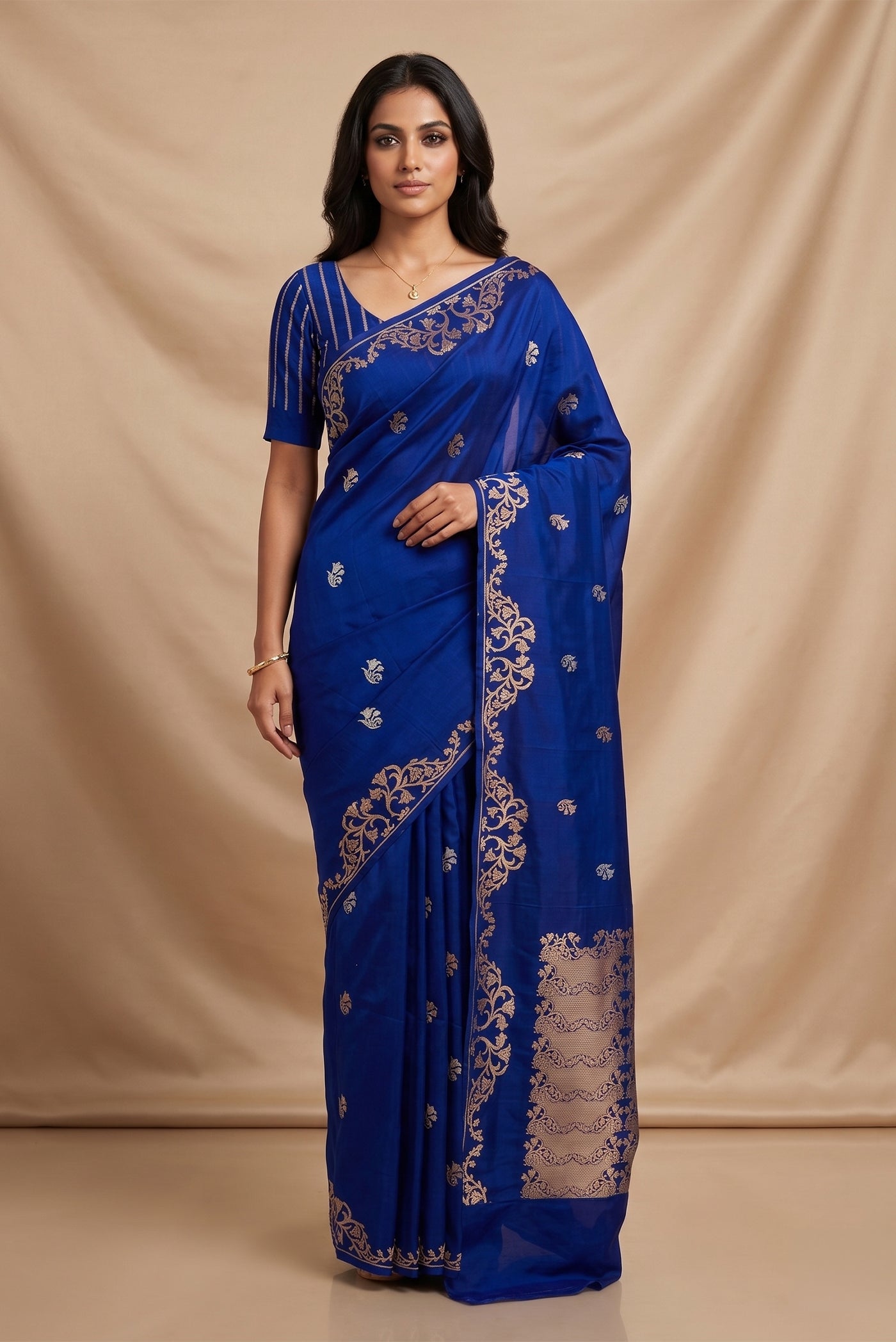 Model wearing a Mrunali, handwoven in Katan silk, features intricate Kadhua borders and delicate gold zari butis. Inspired by the graceful curves of Art Nouveau, its floral border unfolds as a rising vine of bell-shaped blooms, forming a gentle reverse scallop. The rich pallu continues this ornate floral story, while naturalistic butis across the body add a soft shimmer and refined elegance to the saree.