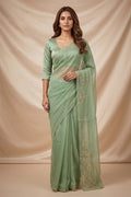Model wearing a Mahira organza saree is inspired by the hydrangea blooms of the Art Nouveau movement. Along the border and edges, bold, simplified hydrangea blooms pair with fluid, curving stems. The flowers gain soft dimension through pani-zari zardozi, while antique-gold aari embroidery adds depth and balance. The pallu features three large asymmetrical butas, formed as flowing clusters of hydrangea blooms and stems, creating a graceful focal point.