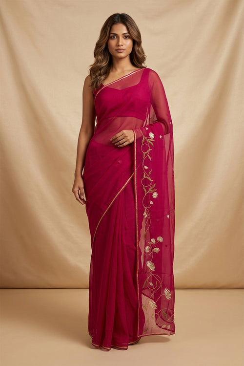 Model wearing a Bahar, crafted in silk organza, features delicate pani-zari enriched with zardozi, gota work, and dabka embroidery. Its defining element is an off-center floral vine running vertically through the body, breaking symmetry with quiet intent. Inspired by Art Nouveau?s flowing lines, the vine is rendered in slender leaves, zari chain-stitched stems, and alternating gota and zardozi flowers. The pallu trails gently onto the body in scattered embroidered blooms.