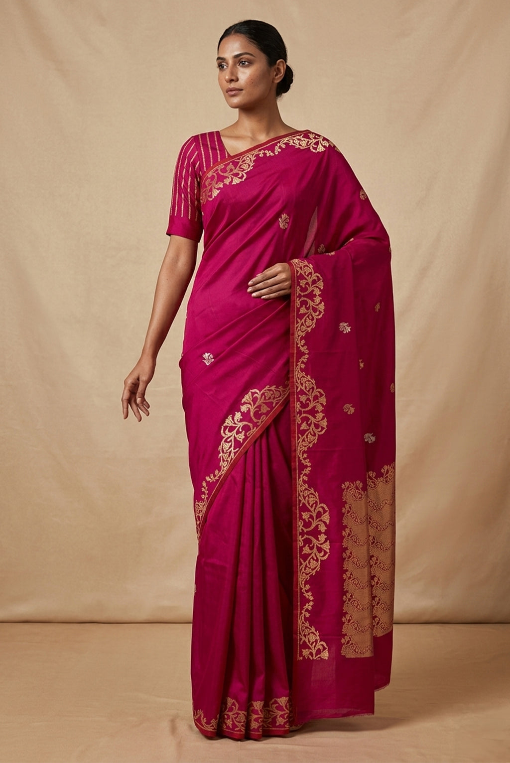 Model wearing a Mrunali, handwoven in Katan silk, features intricate Kadhua borders and delicate gold zari butis. Inspired by the graceful curves of Art Nouveau, its floral border unfolds as a rising vine of bell-shaped blooms, forming a gentle reverse scallop. The rich pallu continues this ornate floral story, while naturalistic butis across the body add a soft shimmer and refined elegance to the saree.