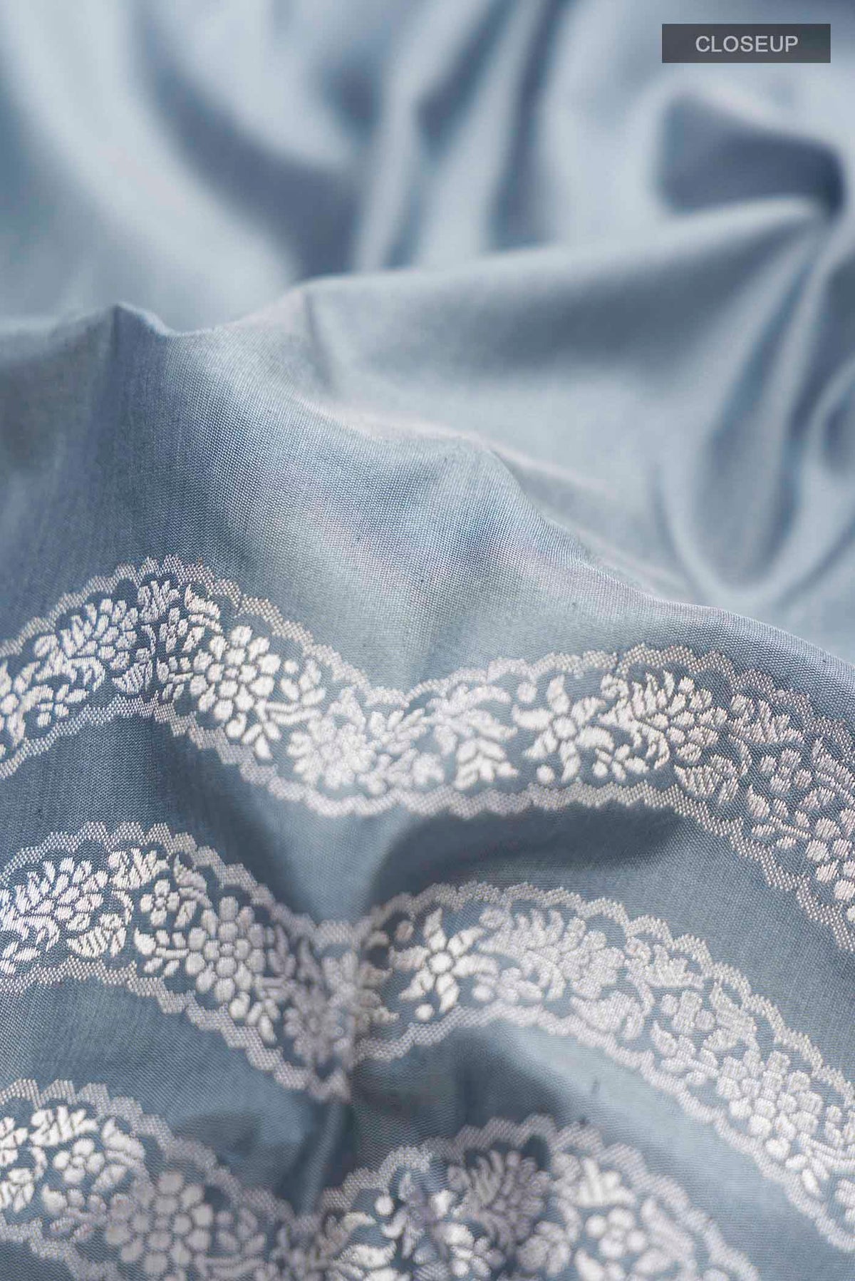 Close up of Grey Banarasi Silk Saree with Plain Body and Zari Border displaying folds