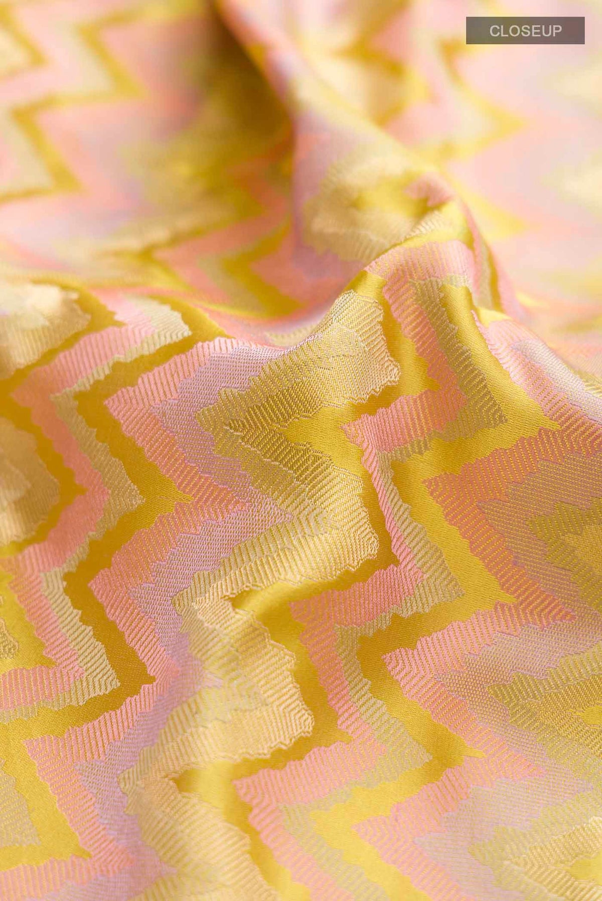 Close up of Yellow Banarasi Silk Saree with Zig Zag design on the body and Zari Border displaying folds