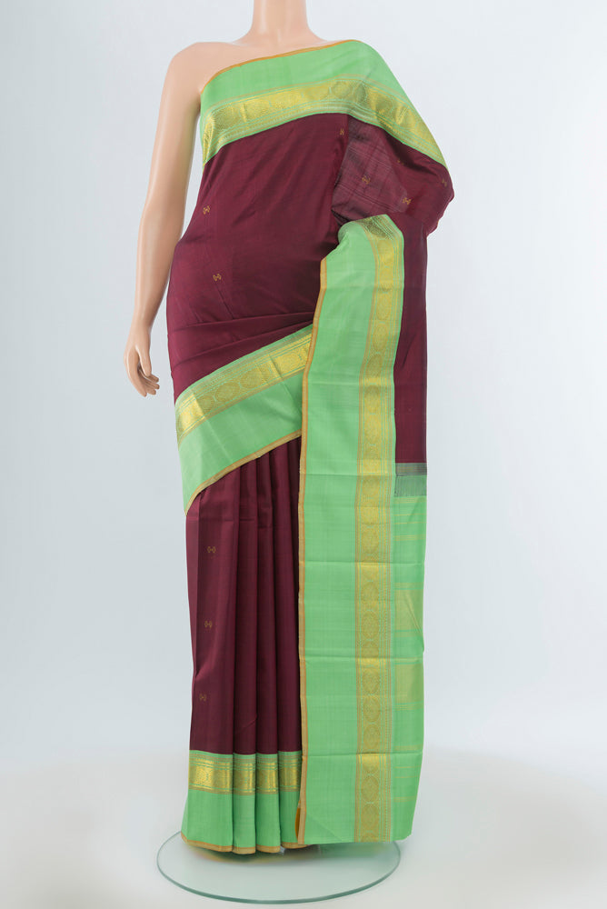 Maroon Kanjivaram Silk Saree with Zari Butta on the body and Silk Border.  displayed on a mannequin