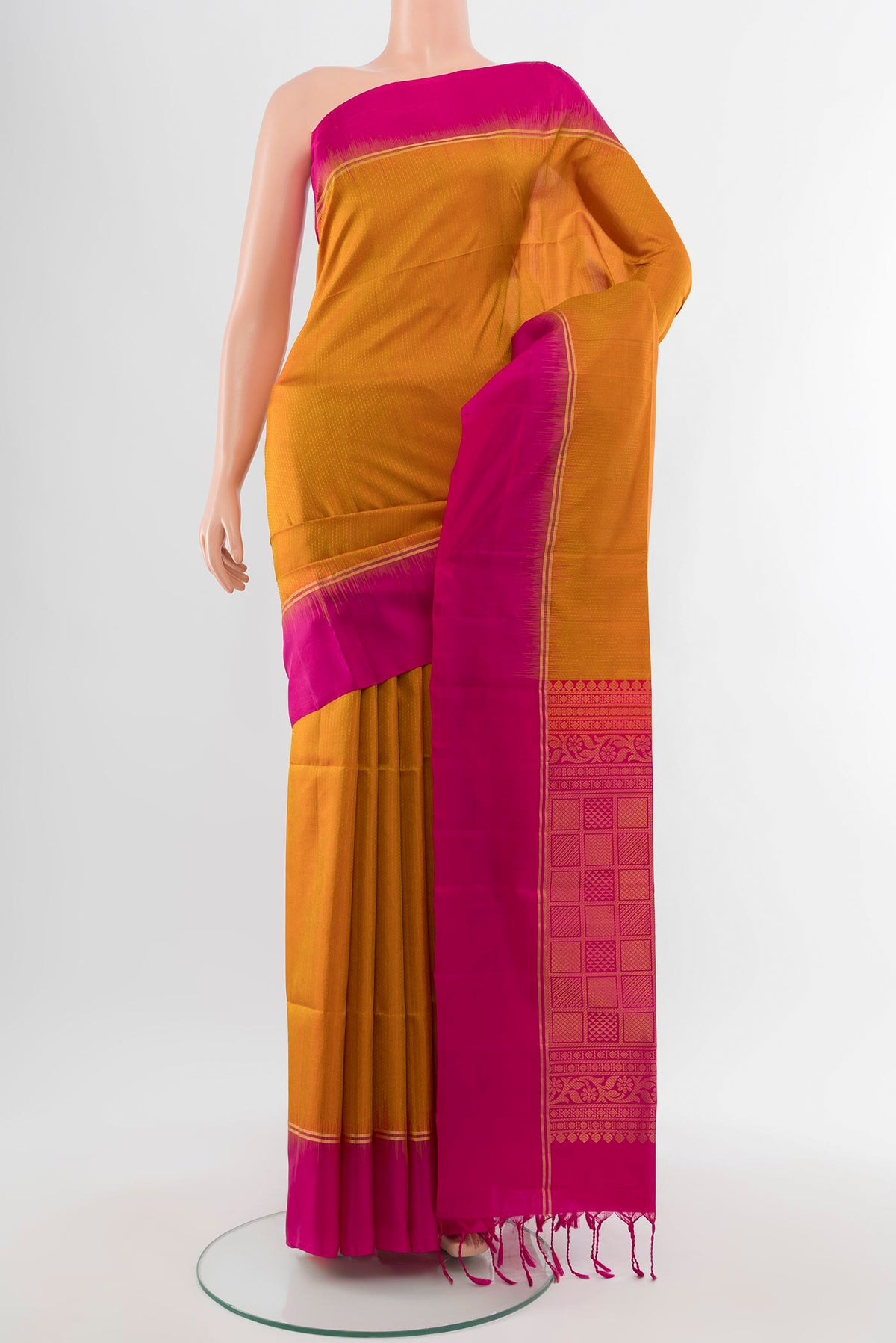 Mustard Soft Silk Saree with Zari Butta on the body and Silk Border.  displayed on a mannequin