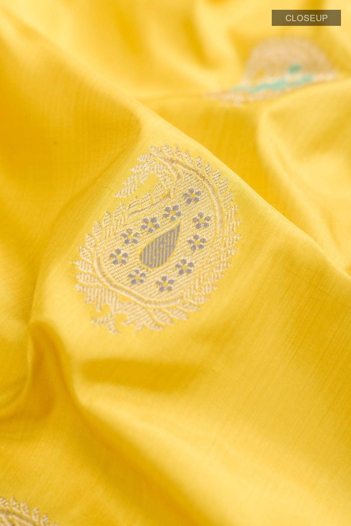 Close up of Yellow Banarasi Silk Saree with Zari Butta on the body and Zari Border displaying folds