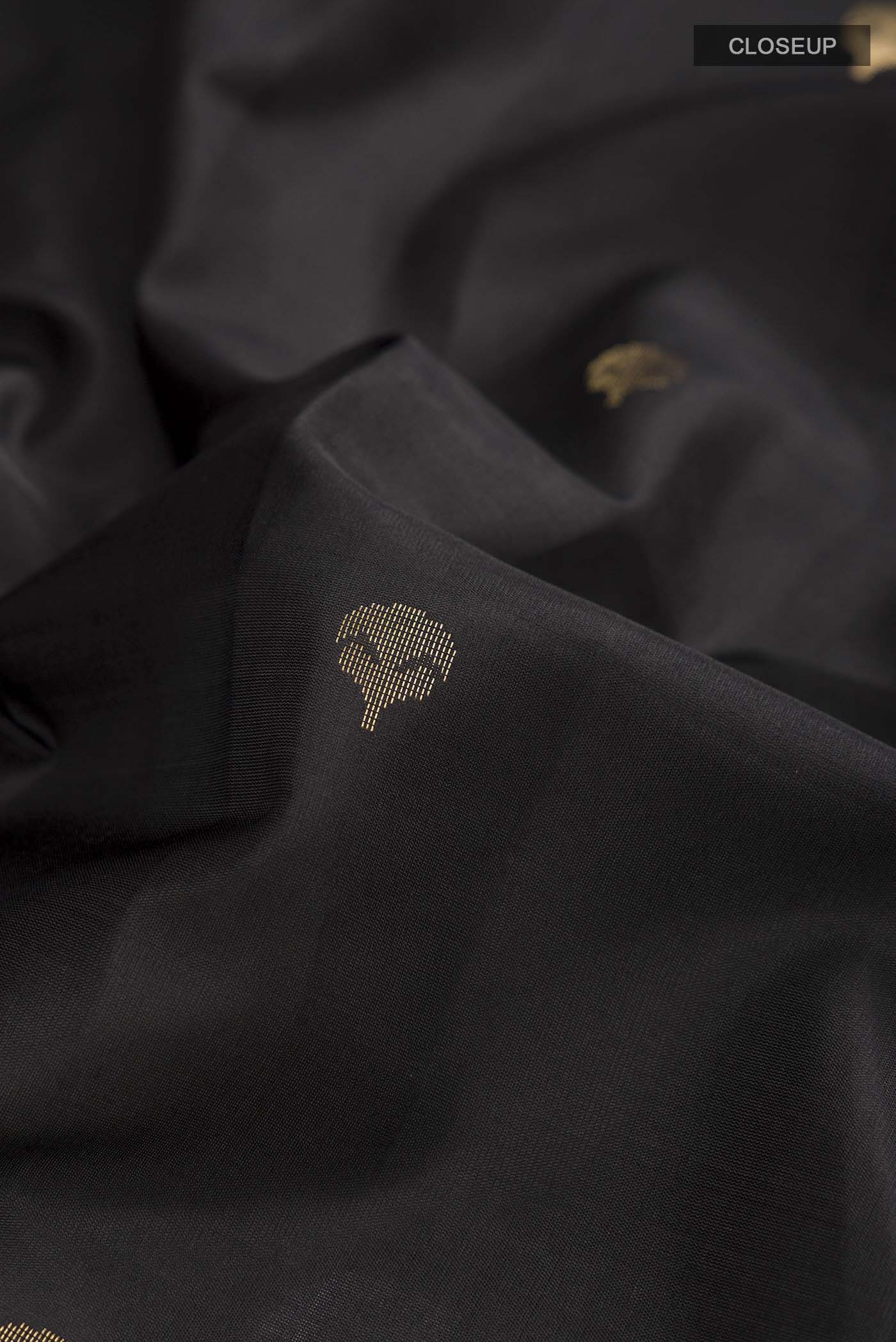 Close up of Black Soft Silk Saree with Zari Butta on the body and Zari Border displaying folds