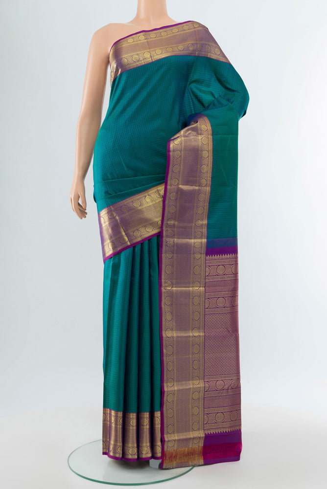 Peacock Blue Kanjivaram Silk Saree with Zari Butta on the body and Silk Border.  displayed on a mannequin