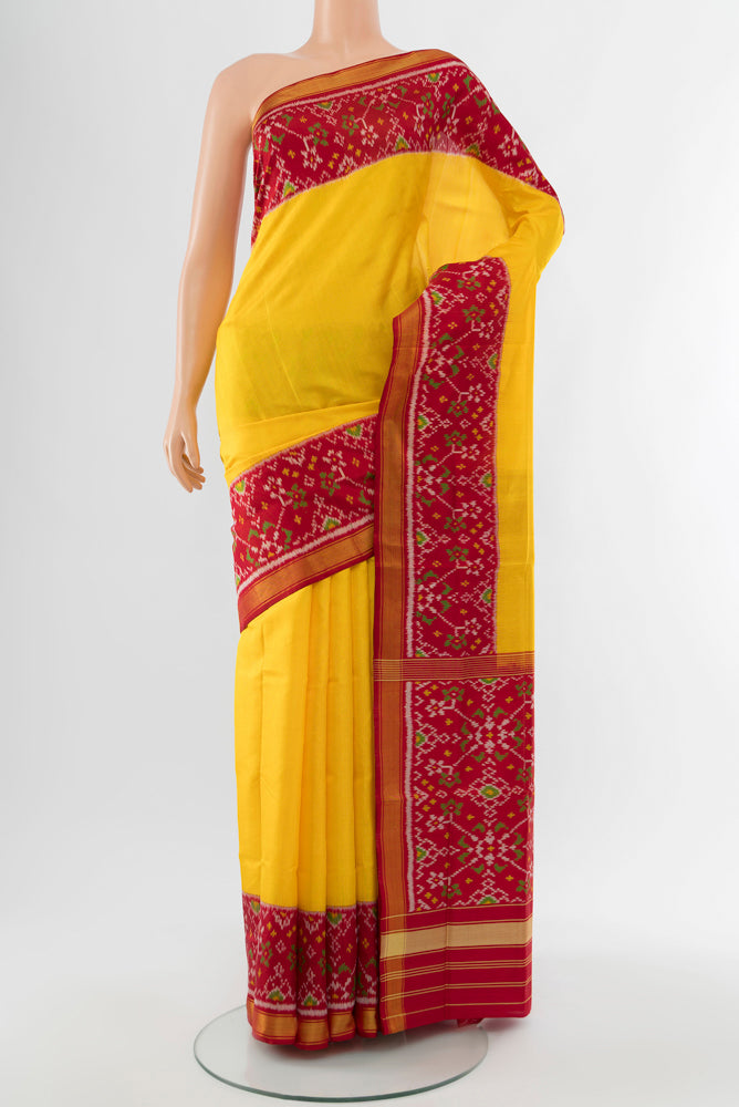 Yellow Rajkot Patola Silk Saree with Ikat Print on the body and Silk Border.  displayed on a mannequin