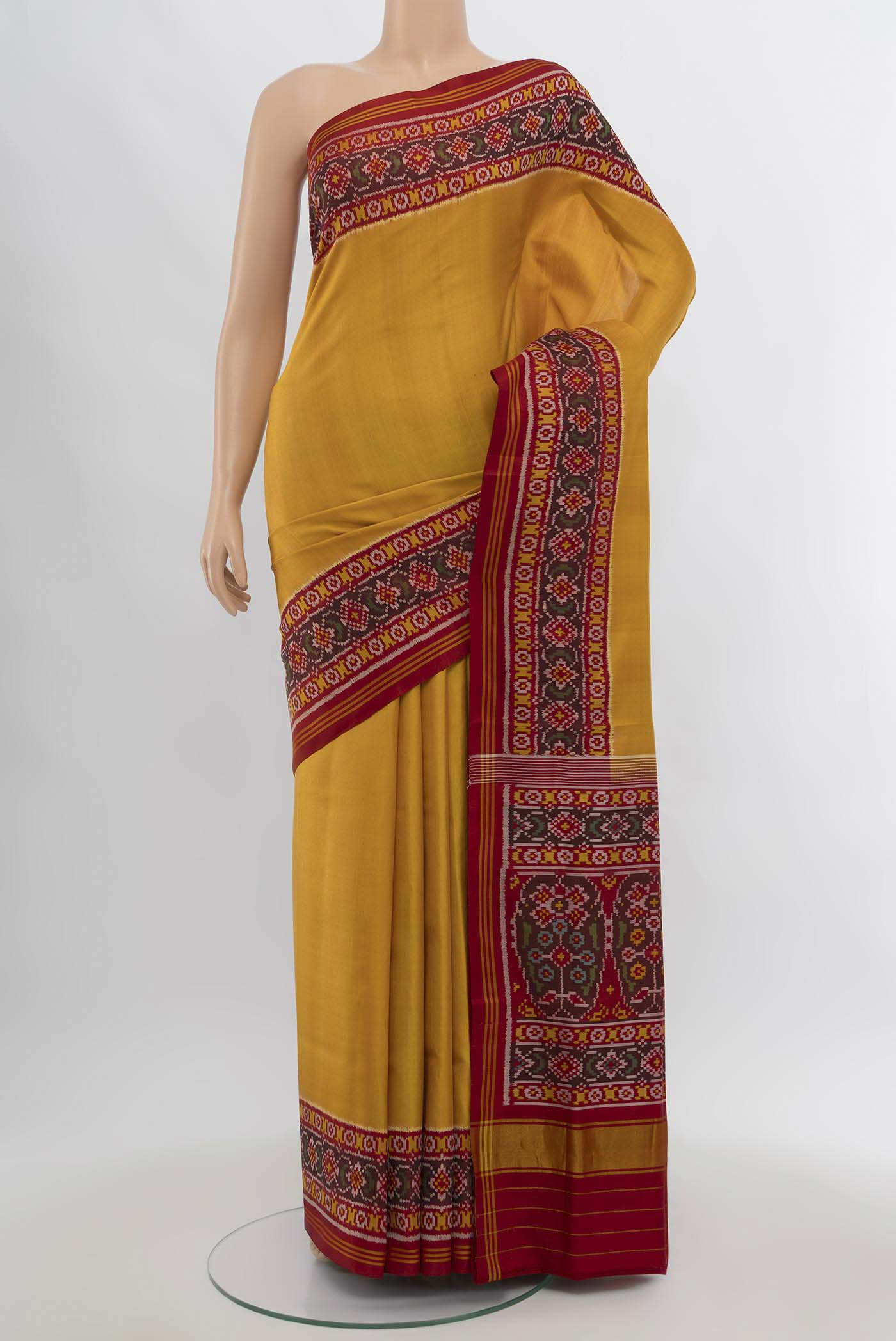 Yellow Rajkot Patola Silk Saree with Ikat Print on the body and Silk Border.  displayed on a mannequin