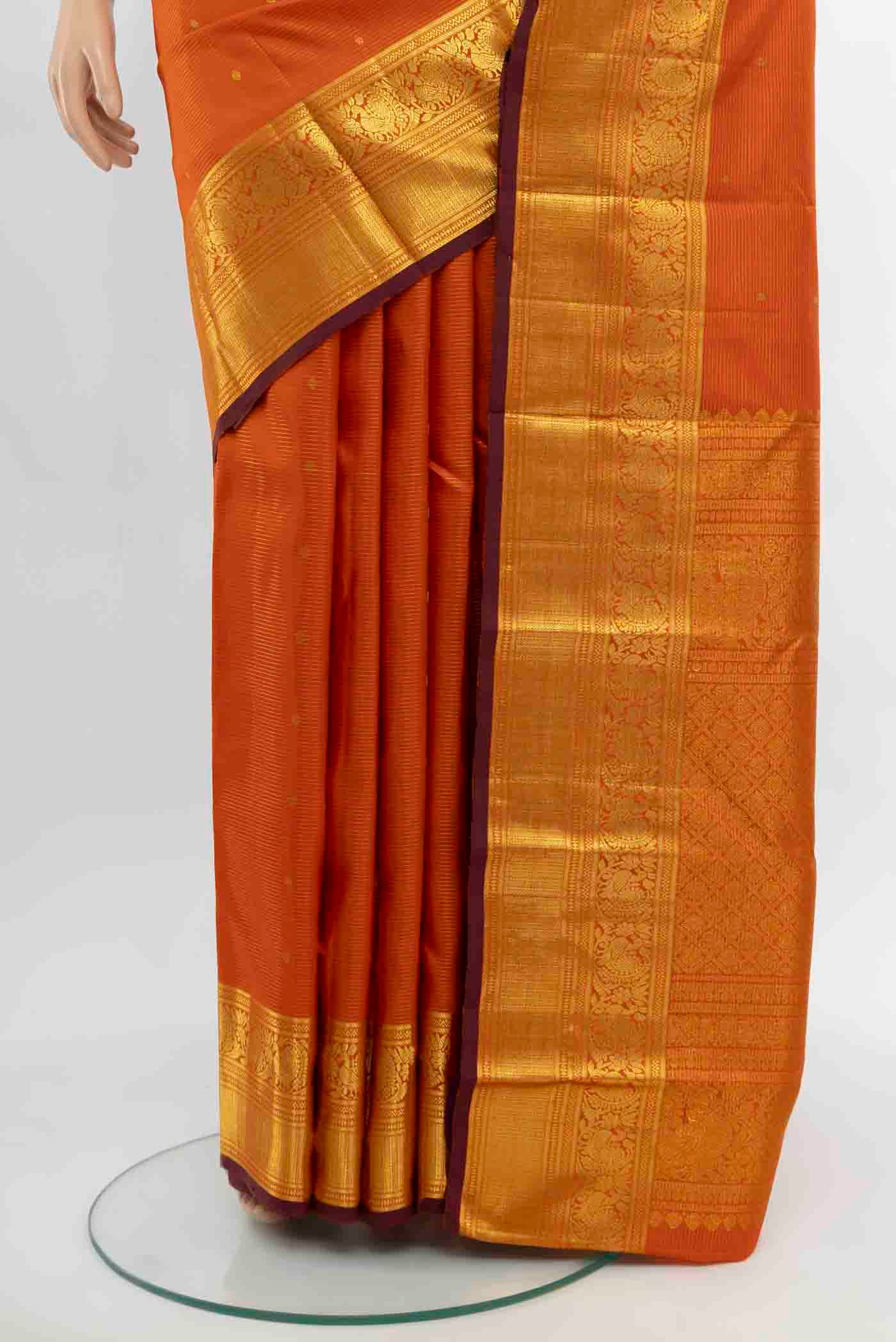 Pleats and pallu of Rust Kanjivaram Silk Saree with Zari Butta on the body and Silk Border. 