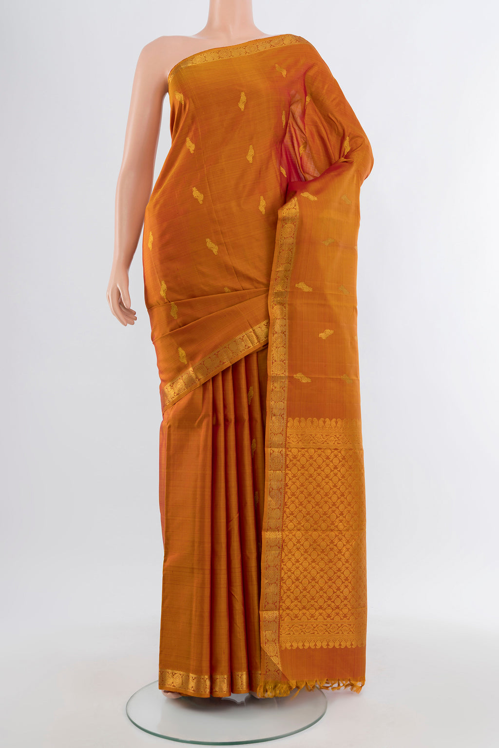 Rust Kanchipuram Silk Saree with Zari Butta on the body and Silk Border.  displayed on a mannequin