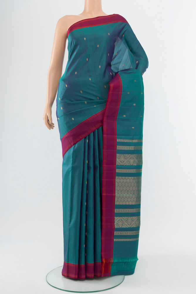 Peacock Blue Kanchipuram Silk Saree with Zari Butta on the body and Silk Border.  displayed on a mannequin